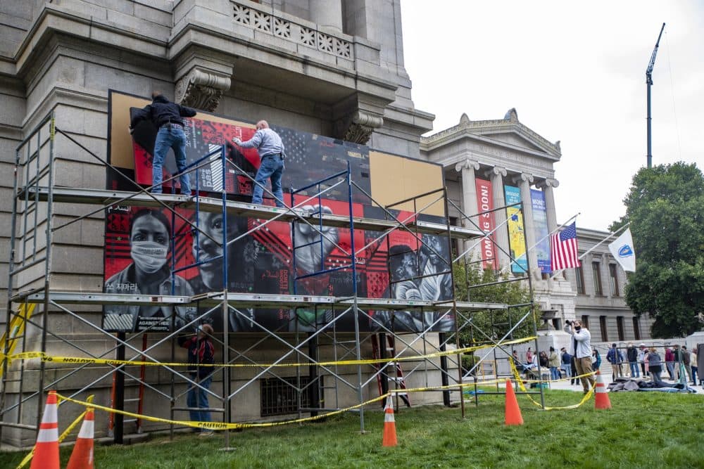 Workers install the new mural on the Huntington Avenue lawn of the Museum of Fine Arts. (Jesse Costa/WBUR)