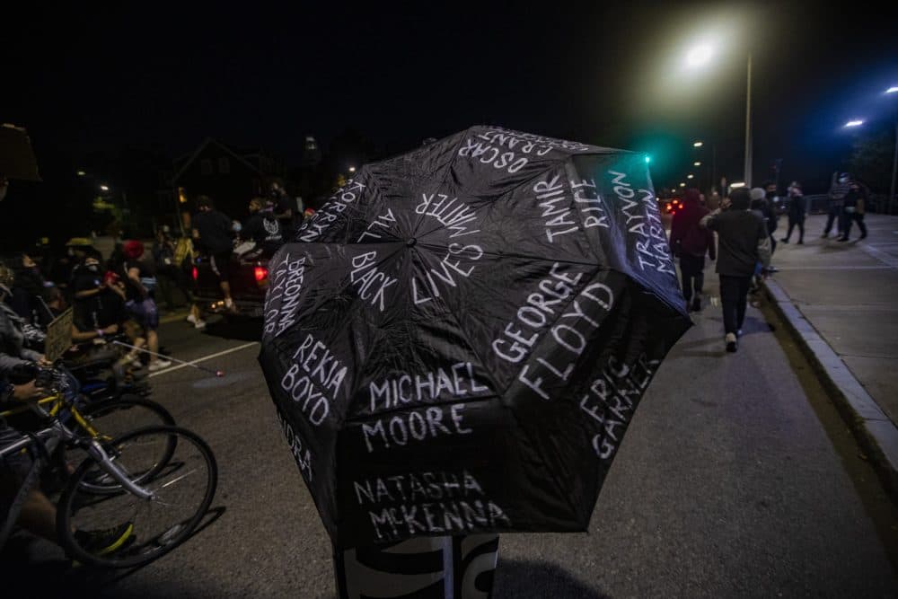 A woman marches down Malcolm X. Boulevard with an umbrella with names of victims killed by police during the Justice for Breonna Taylor rally. (Jesse Costa/WBUR)