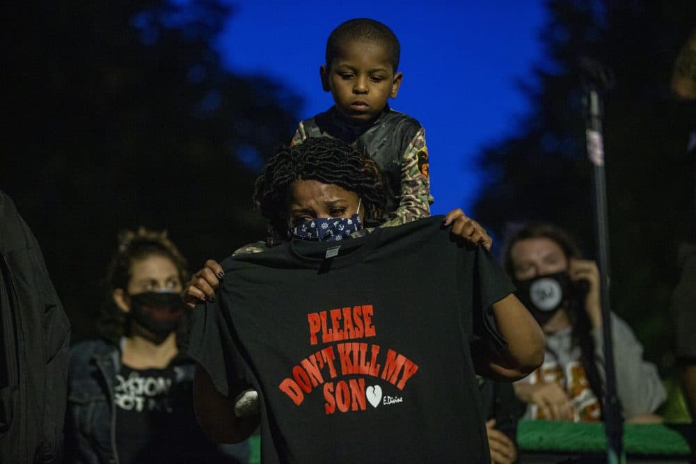 A woman with her son on her shoulders holding up a t-shirt with the words “Please Dont Kill My Son” at the Justice for Breonna Taylor rally at Nubian Square. (Jesse Costa/WBUR)
