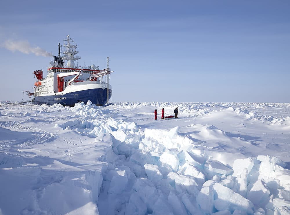 Polarstern drifting in the arctic ice with scientists in the front on the right side. (Alfred-Wegener-Institut/Michael Gutsche)