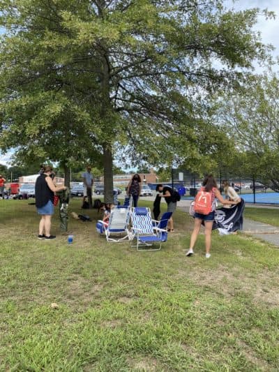 Andover teachers pick up their laptops and lawn chairs to go home after working outside in front of Andover High School on Monday. (Cristela Guerra/WBUR)