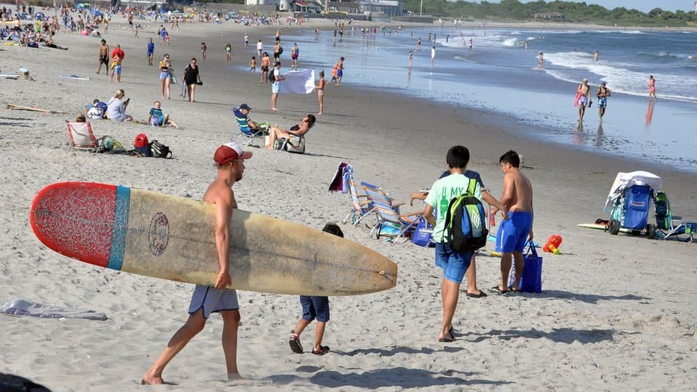 A surfer heads to the water at Narragansett Town Beach on June 25, 2020. (Alex Nunes/The Public's Radio)