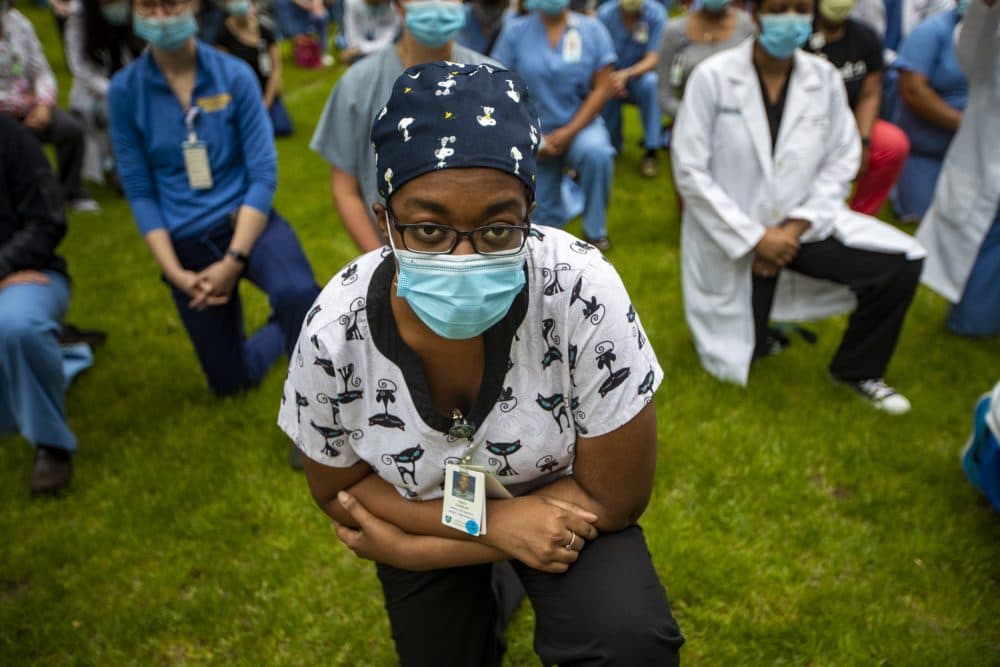 Tracy Charles kneels with hundreds of other staff of the Massachusetts General Hospital participated in a kneel-in, acknowledging the injustice of systemic and individual racism in America, outside the hospital in June. (Jesse Costa/WBUR)