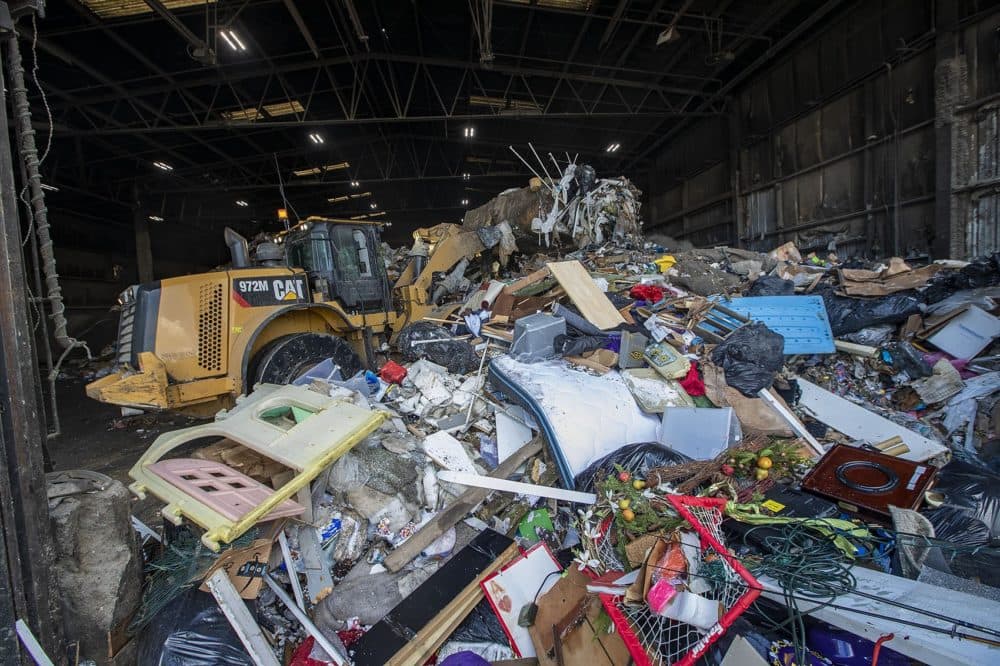 A landmover pushes a 1,000-ton pile of trash into the rear of a warehouse at E.L. Harvey and Sons in Westborough. (Jesse Costa/WBUR)