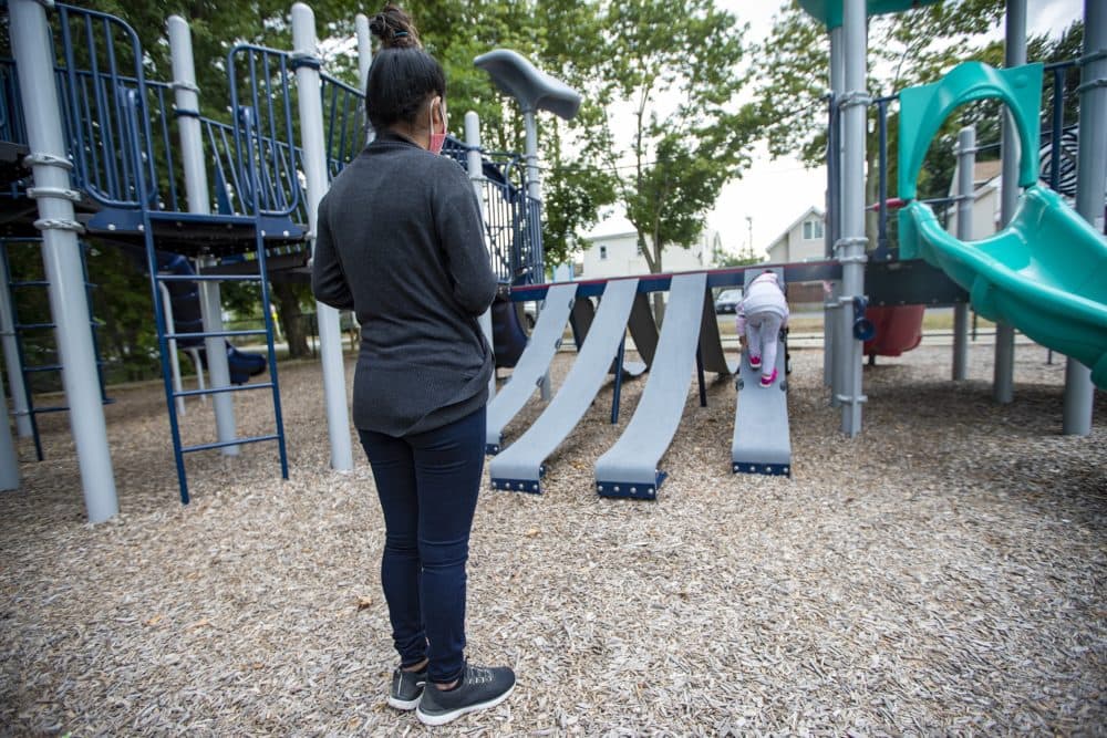 Evila Floridalma Colaj Olmos watches her daughter climb on a slide at a playground near their home in Massachusetts. They are seeking asylum from racial violence in Guatemala. The Trump administration wants them to wait for asylum in Mexico. (Jesse Costa/WBUR)