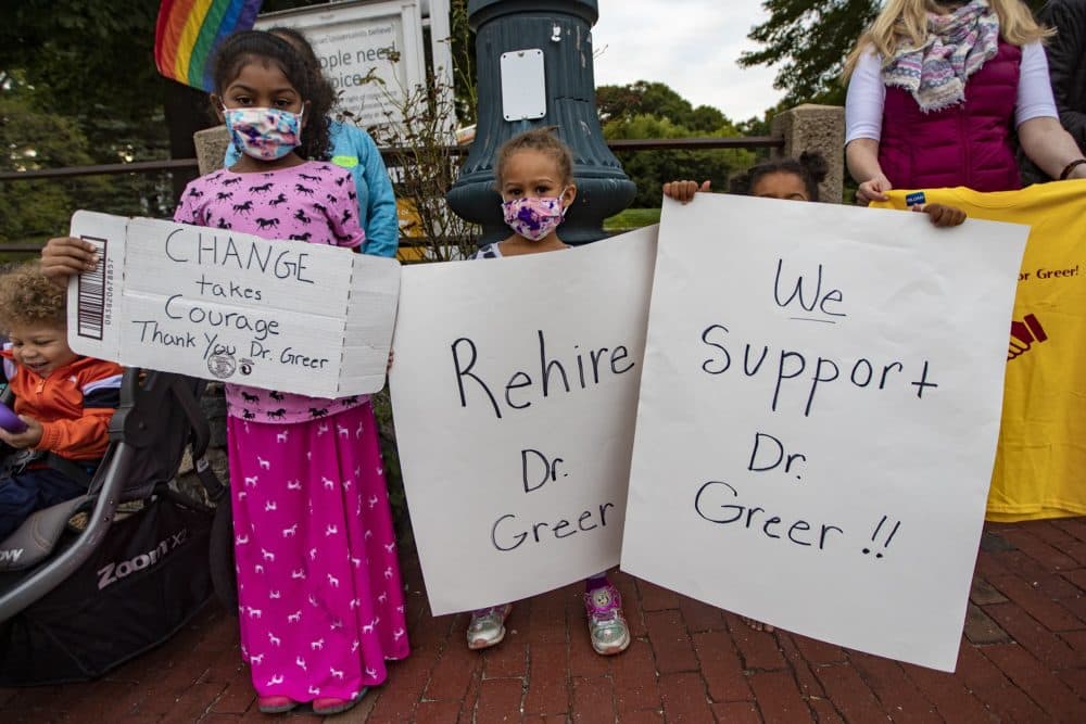 Lillian Nova, 8, Hannah Nova, 5 and Elinor Nova, 3, hold up signs in support of Superintendent Victoria Greer during a rally held in Post Office Square in Sharon in September. (Jesse Costa/WBUR)