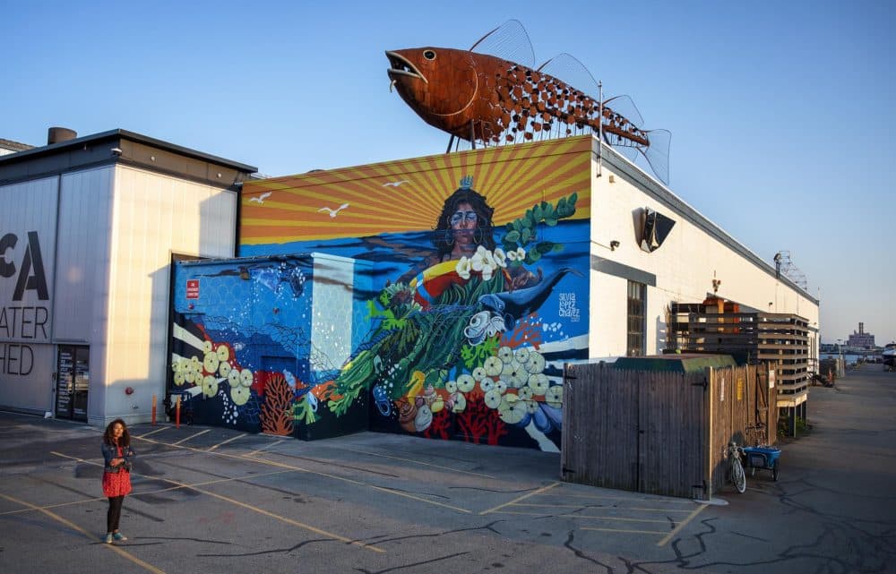 Artist Silvia López Chavez by her mural &quot;Rise&quot; at the Boston Harbor Shipyard and Marina in East Boston. (Robin Lubbock/WBUR)