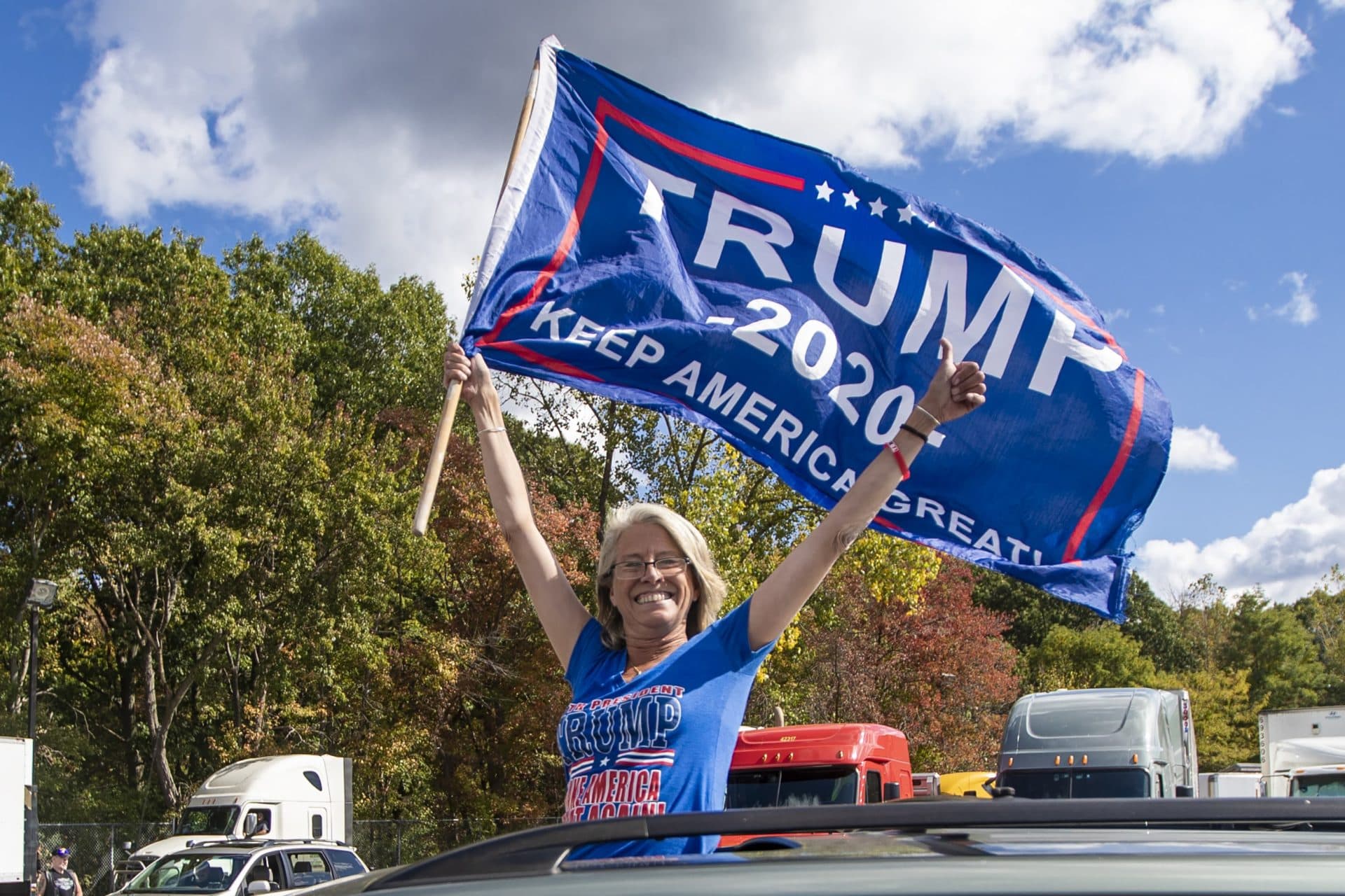 A supporter holds a Trump campaign flag out the sunroof of a car as they leave the Lexington Service Center on Route 95 enroute to the Trump Train rally Londonderry, NH. (Jesse Costa/WBUR)