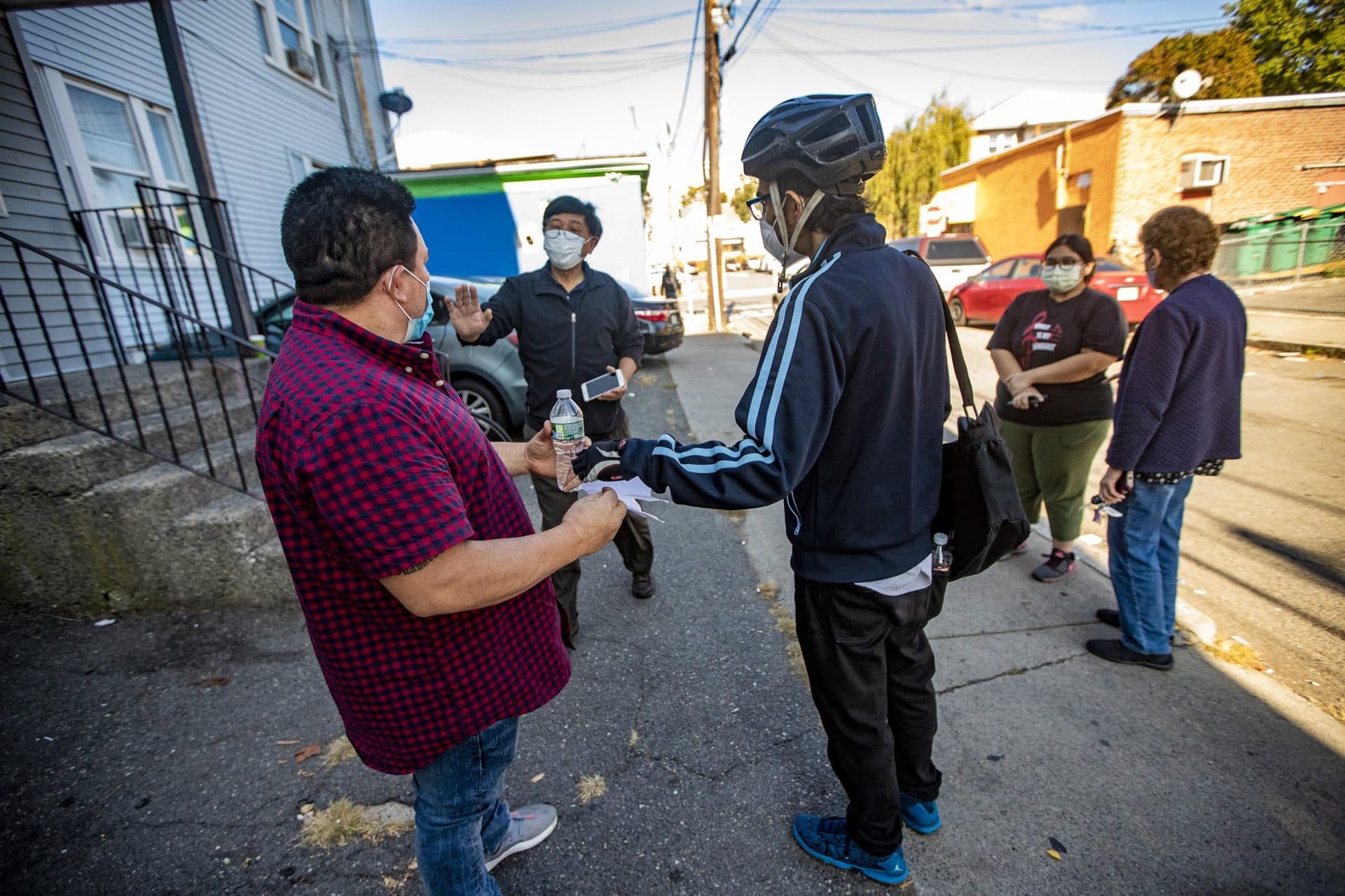 Landlord She Ling Wang walks up to Robelio Gonzalez (left) after Gonzalez was briefly detained by ICE agents outside the Lynn apartment. (Jesse Costa/WBUR)