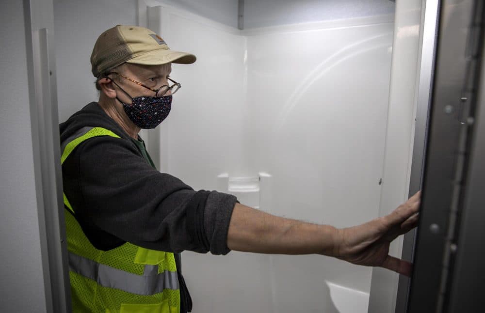 Jim Stewart check over one of the shower stalls in the mobile unit. (Robin Lubbock/WBUR)