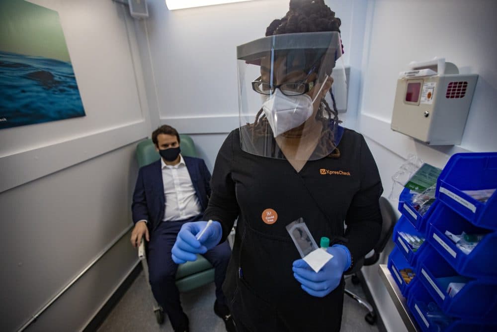 Medical assistant Aneka Gopaulsingh removes a swab from its packaging to conduct a nasal swab test on XpresCheck project manager Julian Bernstein during a demonstration Wednesday morning. (Jesse Costa/WBUR)