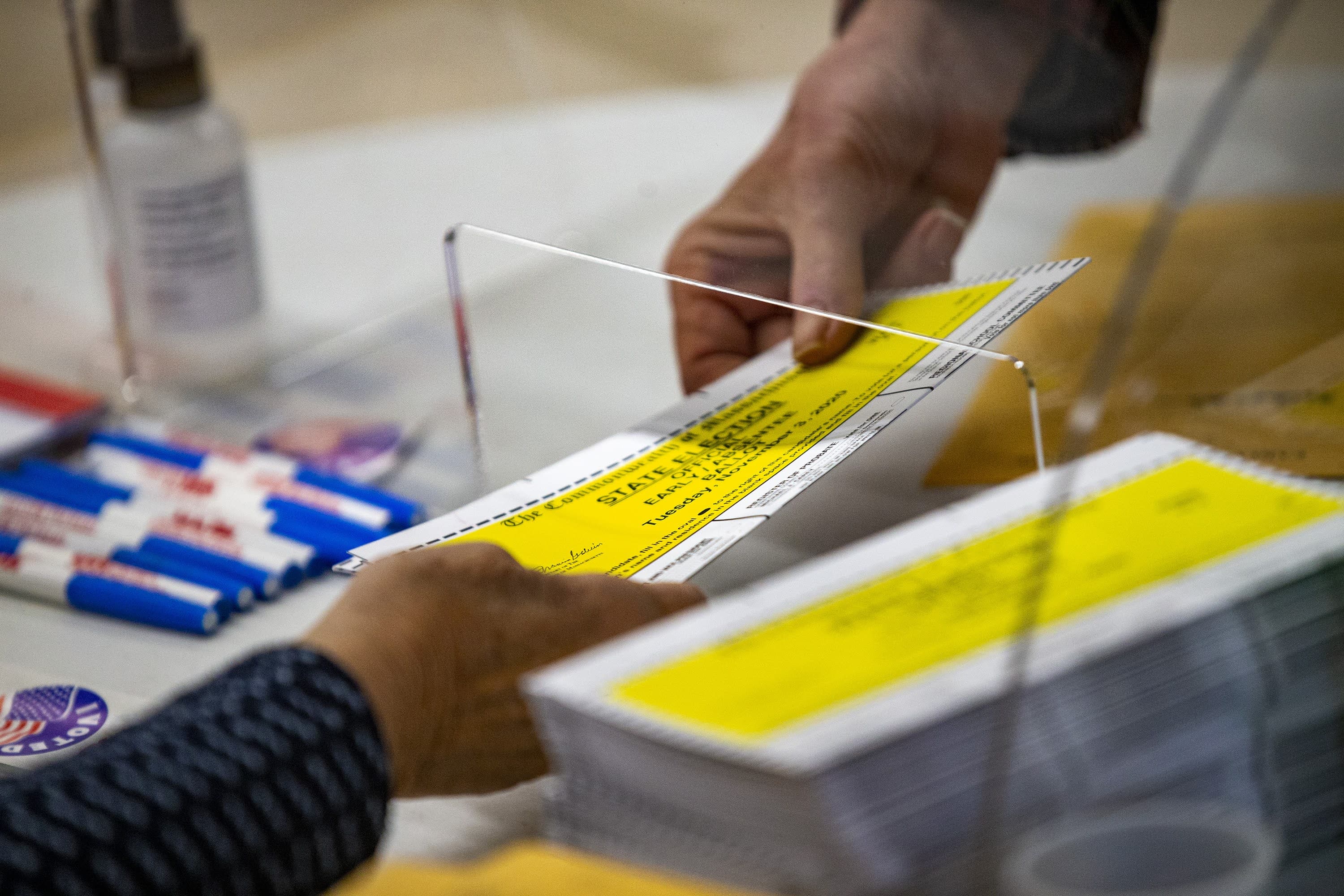 Poll worker Rose Marie Leeman hands a ballot to Kendall Gilmore during early voting at the Senior Center in Ware. (Jesse Costa/WBUR)