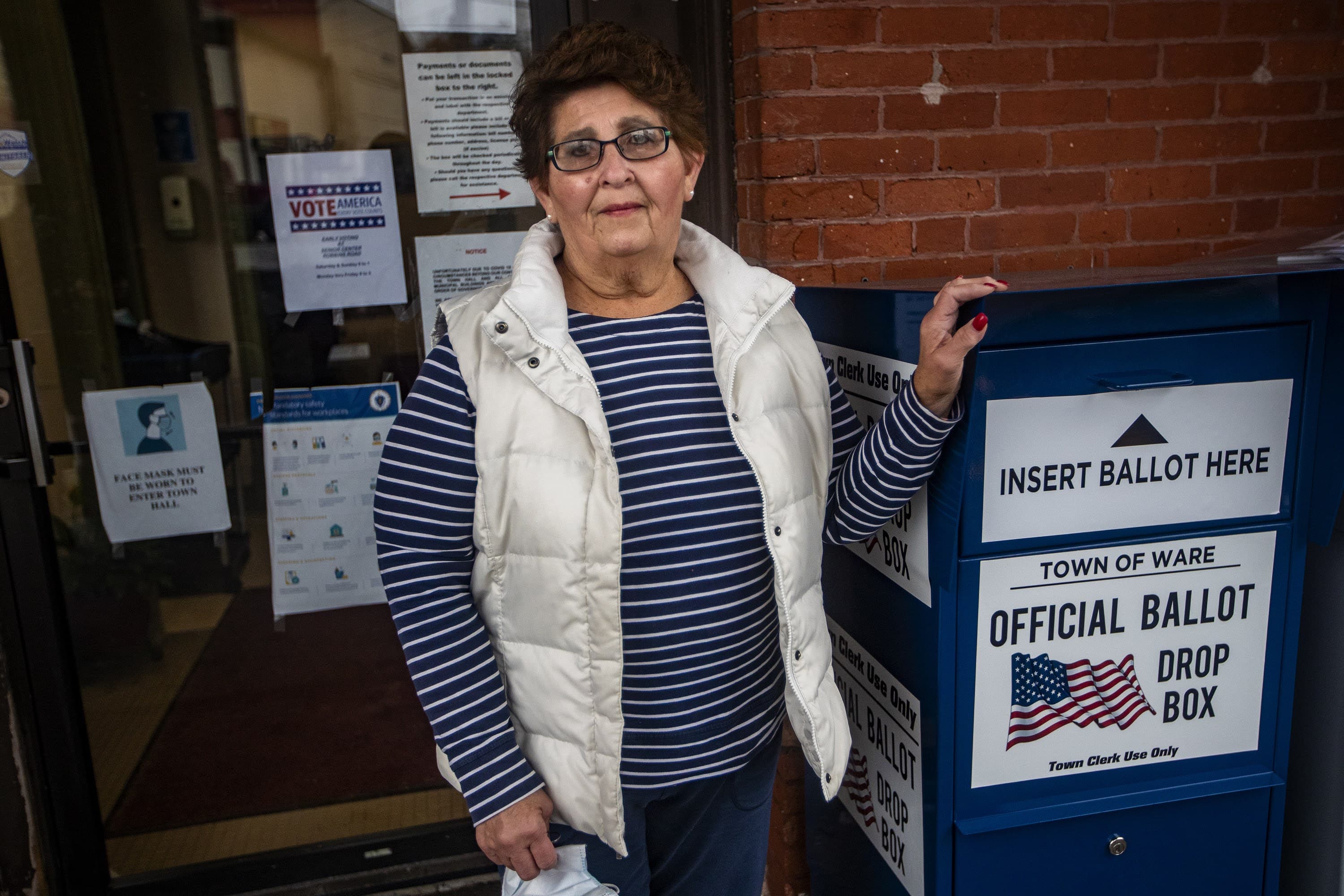 Ware Town Clerk Nancy Talbot stands next to a ballot drop box outside of town hall. (Jesse Costa/WBUR)