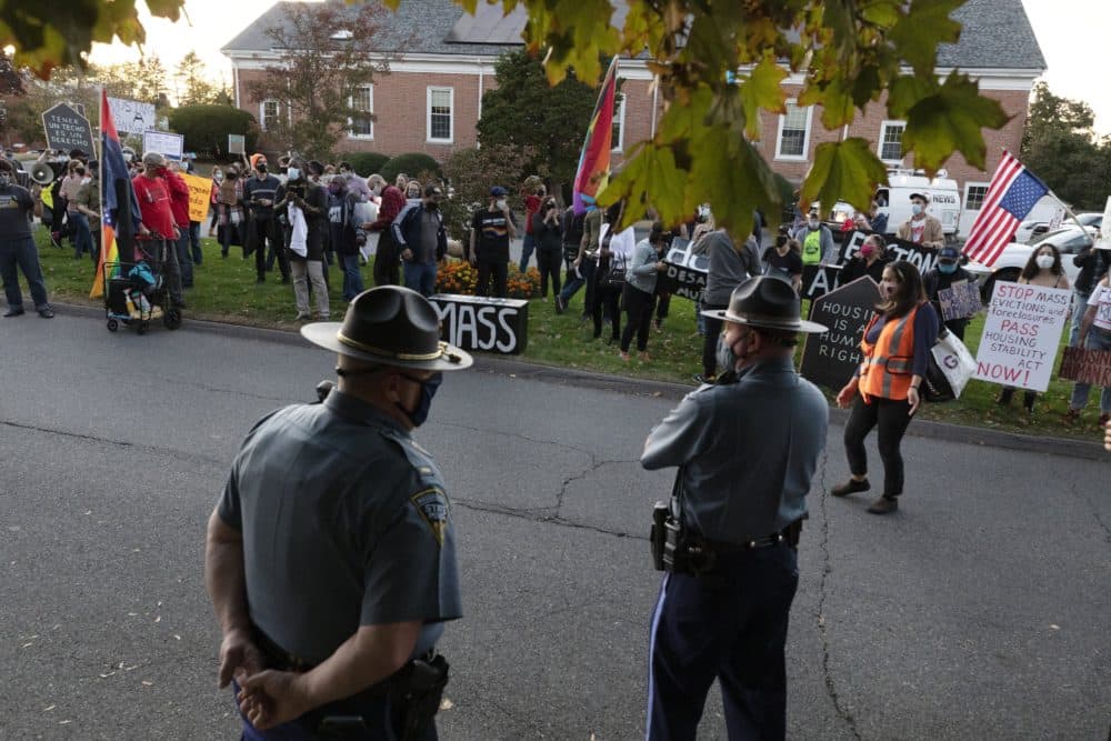 State police look on as housing activists gather in front of Baker's house Wednesday. (Michael Dwyer/AP)