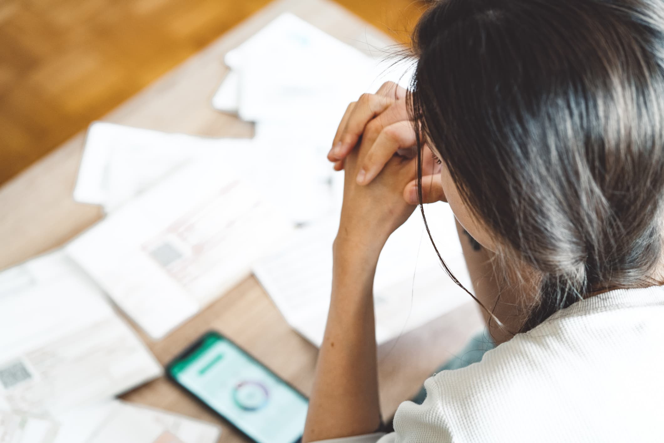 Young woman sitting on the sofa, looking at her bills. (Getty Images)
