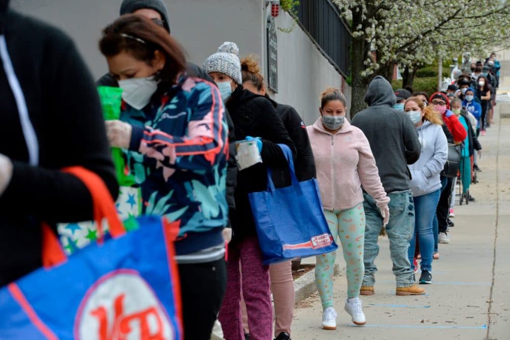 Hundreds of people line up to receive food and goods distributed by volunteers from the Chelsea Collaborative Inc. outside the Pan Y Cafe in Chelsea, Massachusetts on April 14, 2020. (Joseph Prezioso/ AFP via Getty Images)