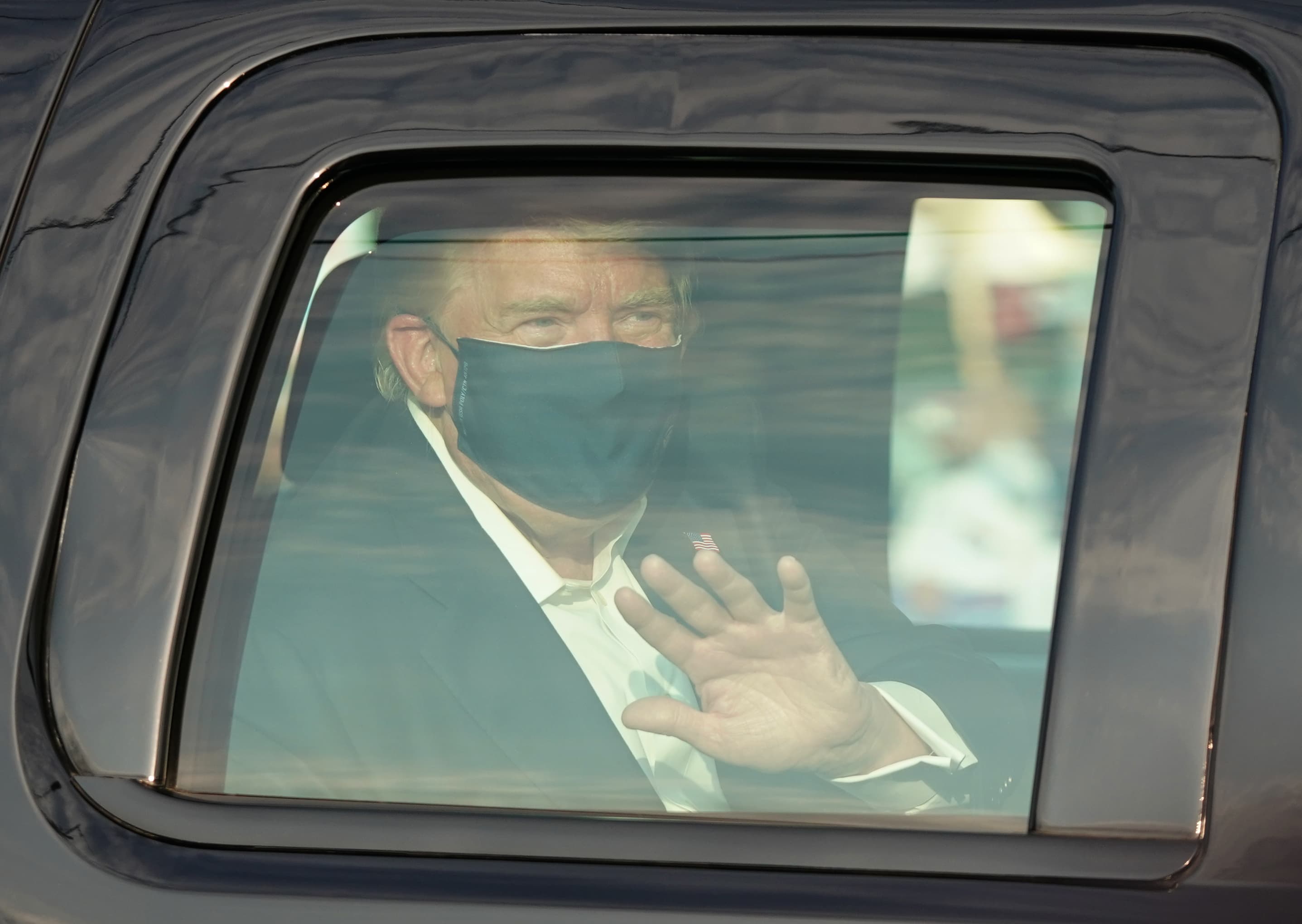 President Trump waves from the back of a car in a motorcade outside of Walter Reed Medical Center in Bethesda, Maryland on Oct. 4, 2020. (Alex Edelman/AFP via Getty Images)