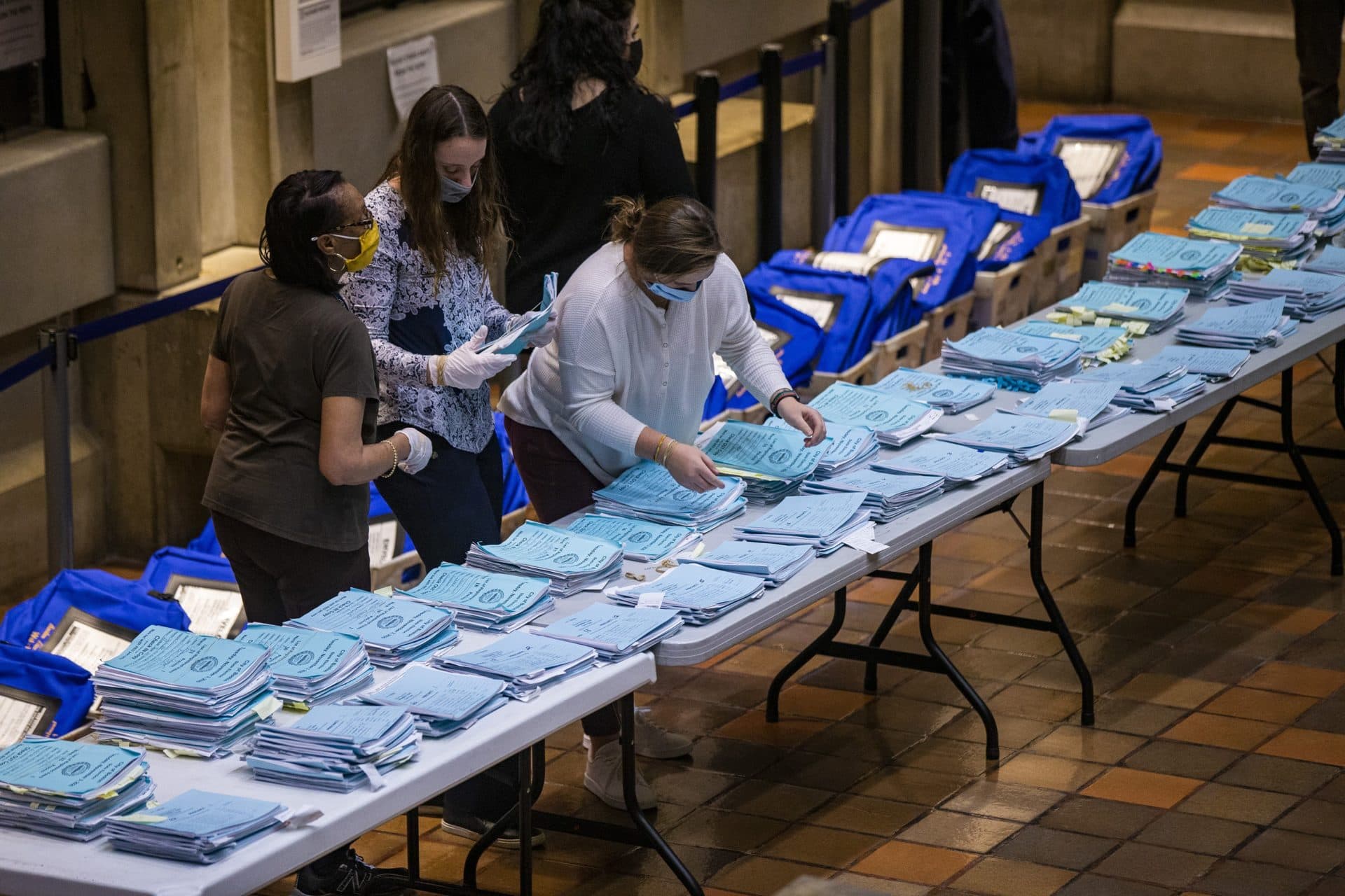 Election workers at Boston City Hall organize voting clerk’s notebooks. (Jesse Costa/WBUR)