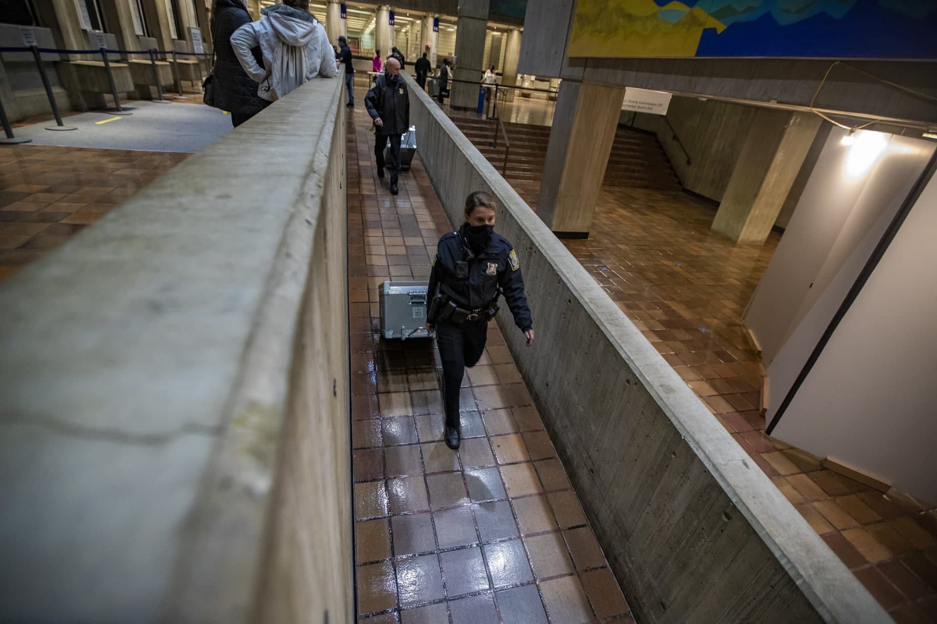 Boston Police officers with trunks of ballots head down a ramp toward a vault located in the lower levels of City Hall. (Jesse Costa/WBUR)
