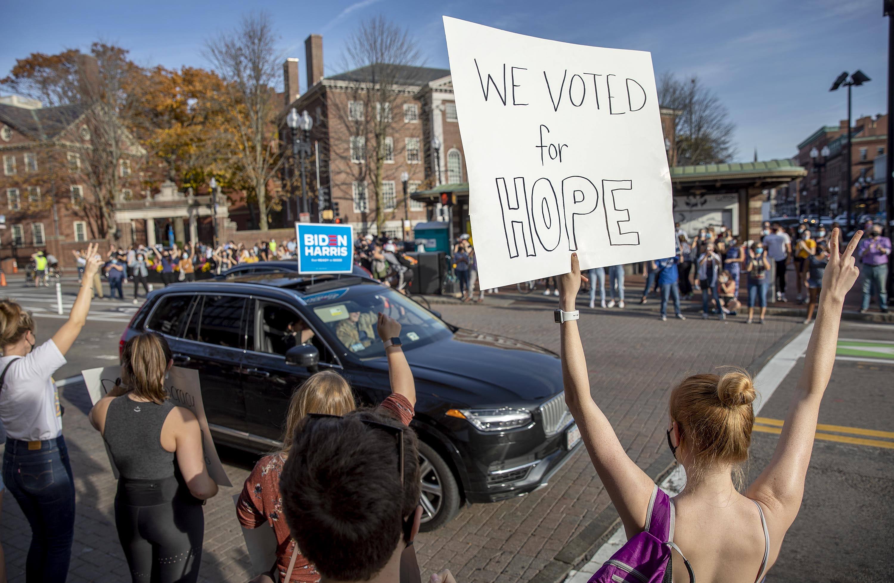 A woman holds up a sign saying "We Voted For Hope" as the crowd in Harvard Square celebrates Biden's election. (Robin Lubbock/WBUR)