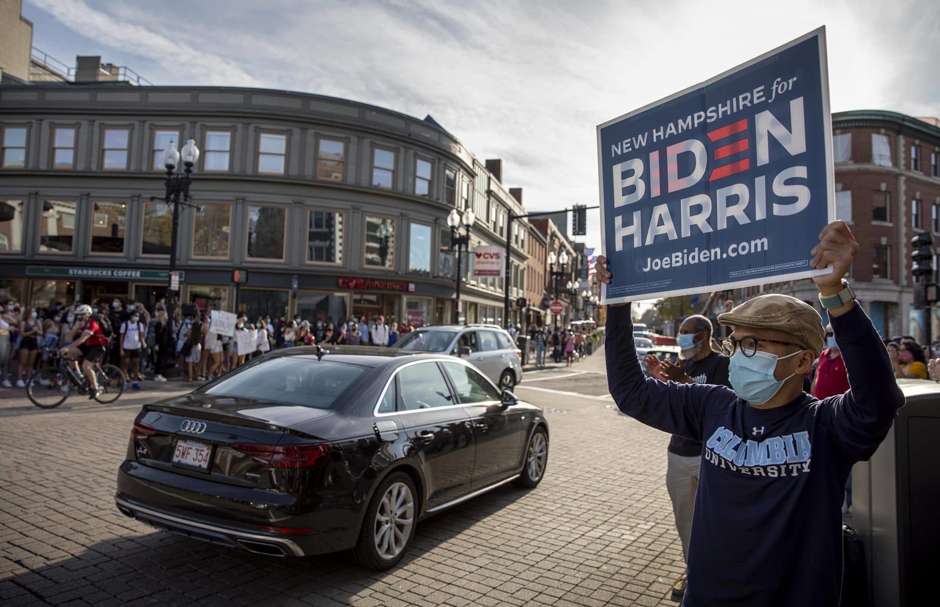 A man holds up a Biden Harris sign at the impromptu election victory celebration in Harvard Square. (Robin Lubbock/WBUR)