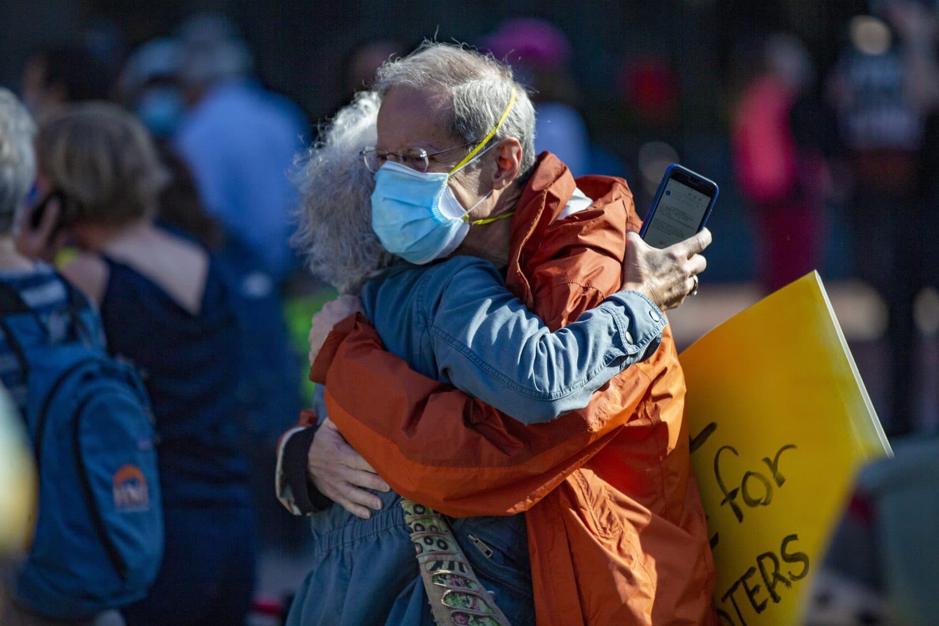 Sherry Flashman and Lee Cranberg of Brookline embrace shortly after the announcement Joe Biden has become the president-elect at the Sunrise Movement and labor groups rally at Copley Square. (Jesse Costa/WBUR)