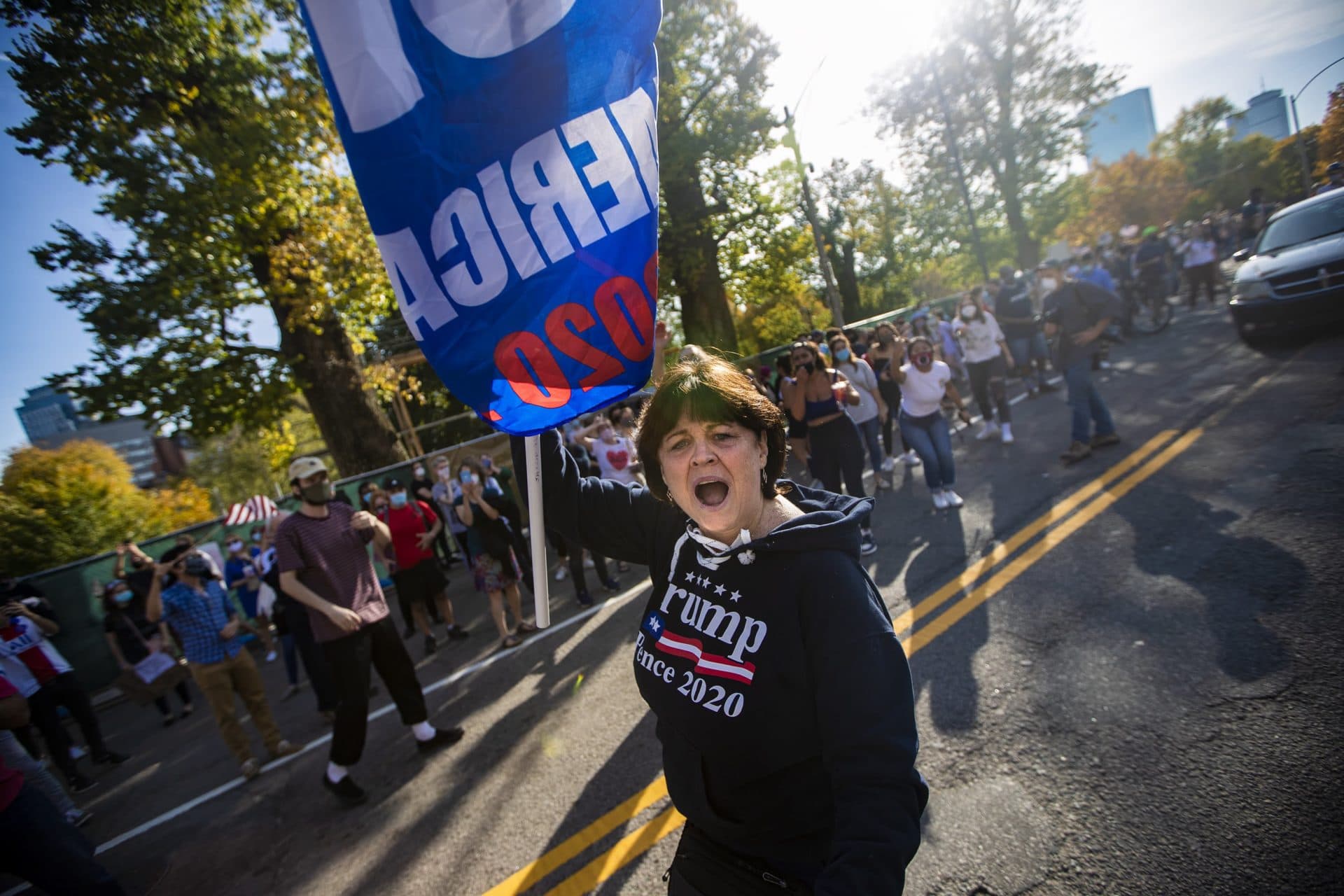 A Trump supporter walks out into the middle of Beacon Street amid Biden counter protesters during a Trump rally in front of the Massachusetts State House. (Jesse Costa/WBUR)