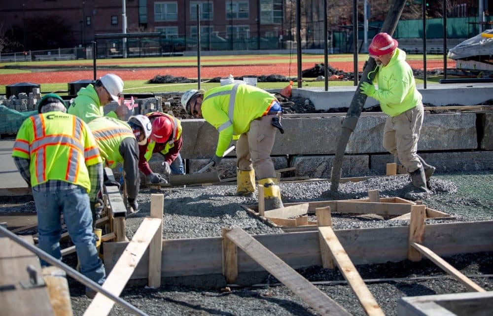 A construction crew pours and levels concrete at Langone Park. (Robin Lubbock/WBUR)