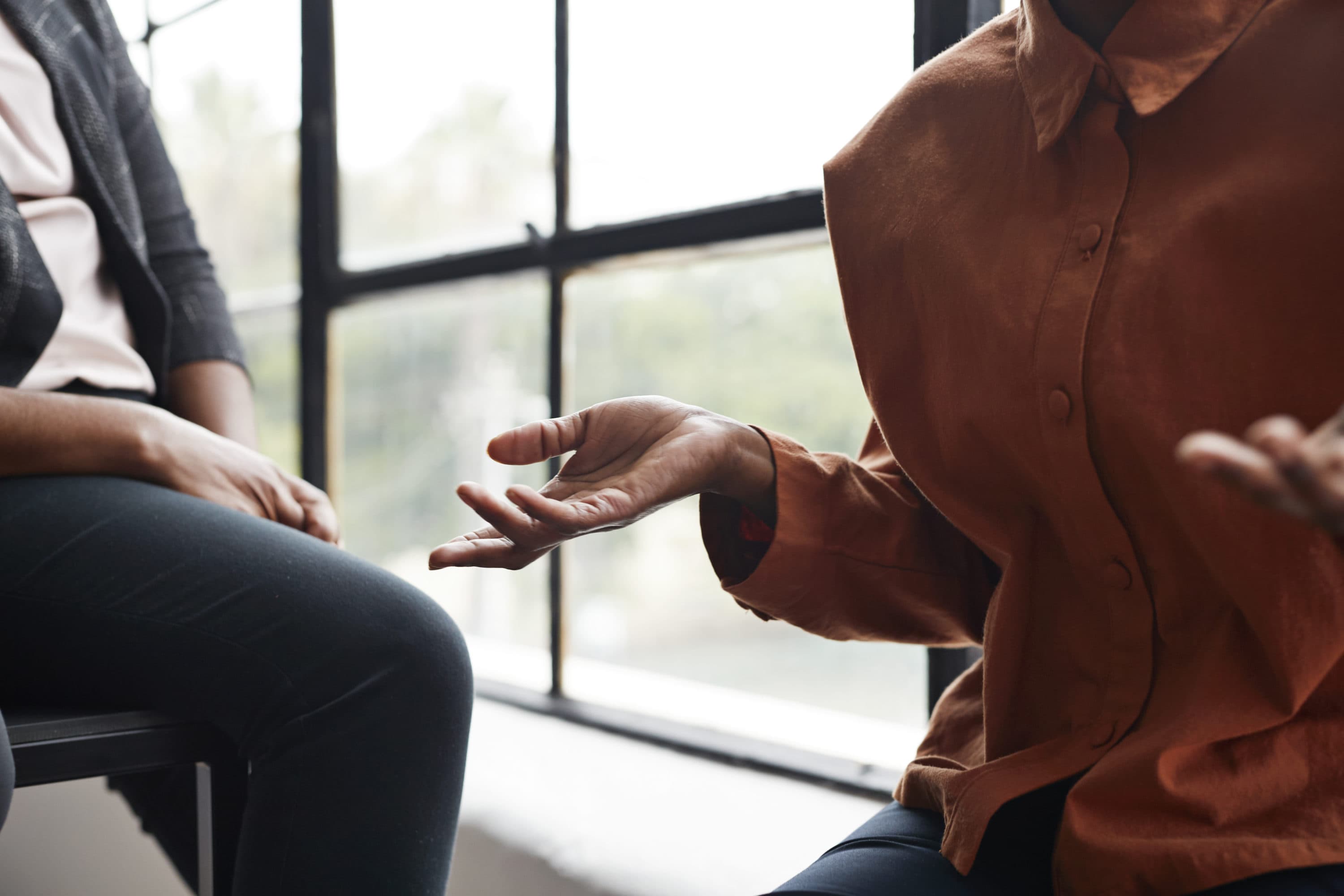 A businesswoman gesturing while sitting by window at workplace. (Getty)
