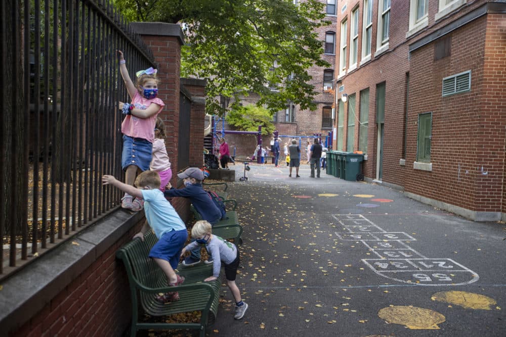 Kids climb the playground fences the Eliot School in the North End in Boston on Oct. 22, 2020. Starting in December, some school students will have access to rapid COVID-19 tests. (Stan Grossfeld/The Boston Globe via Getty Images)