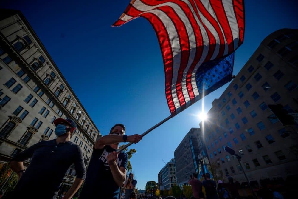 A man waves a U.S. flag as people celebrate in Washington, D.C., after Joe Biden was declared the winner of the 2020 presidential election. (Eric Baradat/AFP/Getty Images)