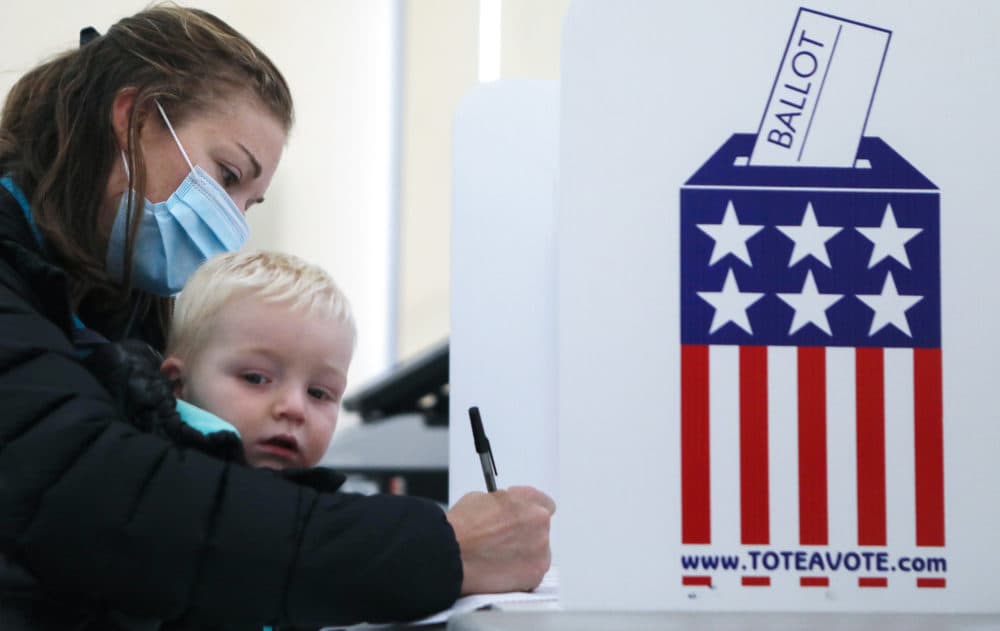 A voter sits with a child as she fills out her ballot during early voting in the 2020 presidential election on October 29, 2020 in Adel, Iowa. (Mario Tama/Getty Images)