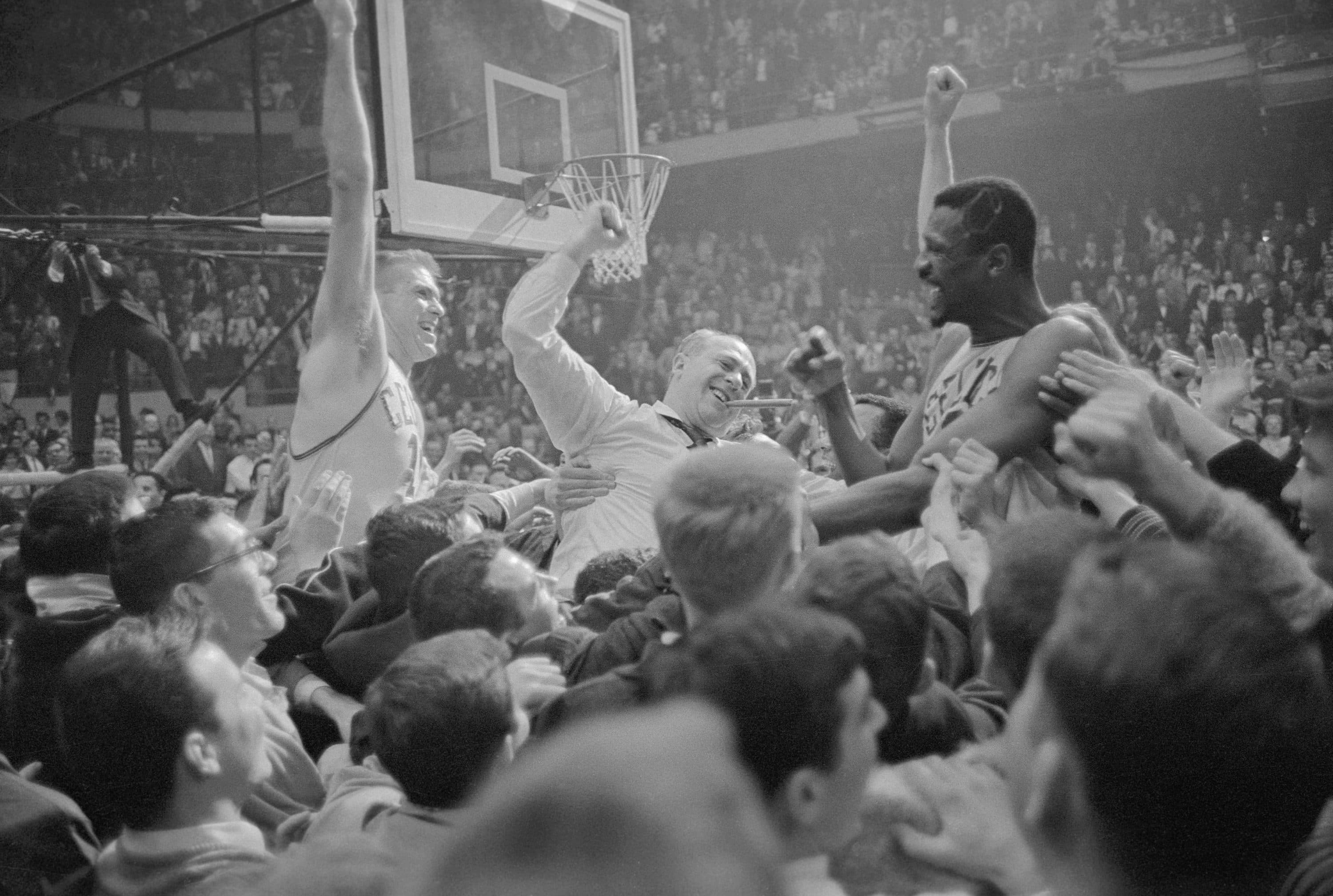Jubilant fans carry Celtics' Tommy Heinsohn (left), coach Red Auerbach (Center, with victory cigar), and Bill Russell (right) around the basketball court at Boston Garden after the Celtics won their sixth consecutive World's Championship in 1964. (Getty Images)