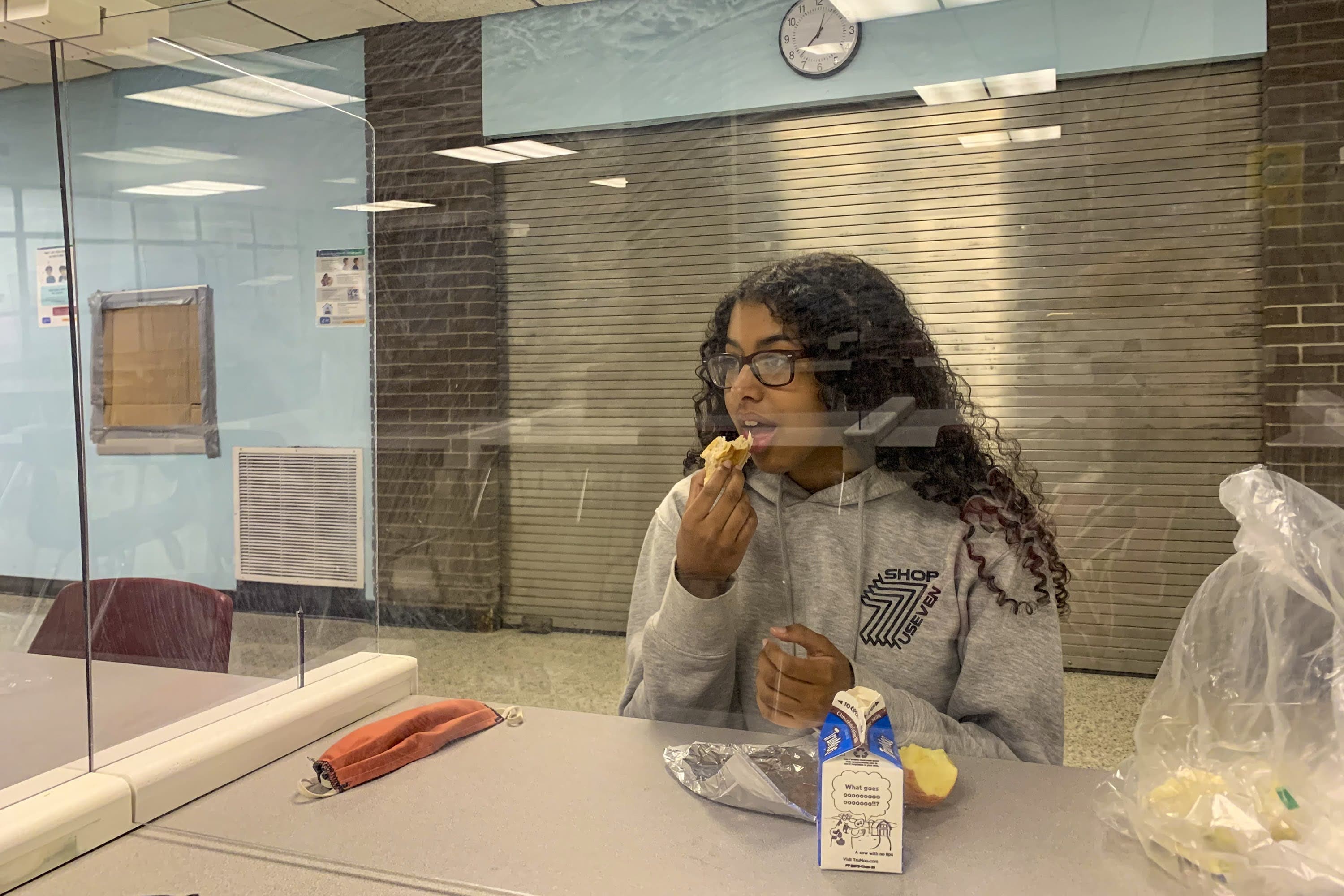 Senior Jessica Brito eats lunch while separated from her classmates by plexiglass. The barrier allows students to take their masks off to eat. (Courtesy Maxine DeJesus)