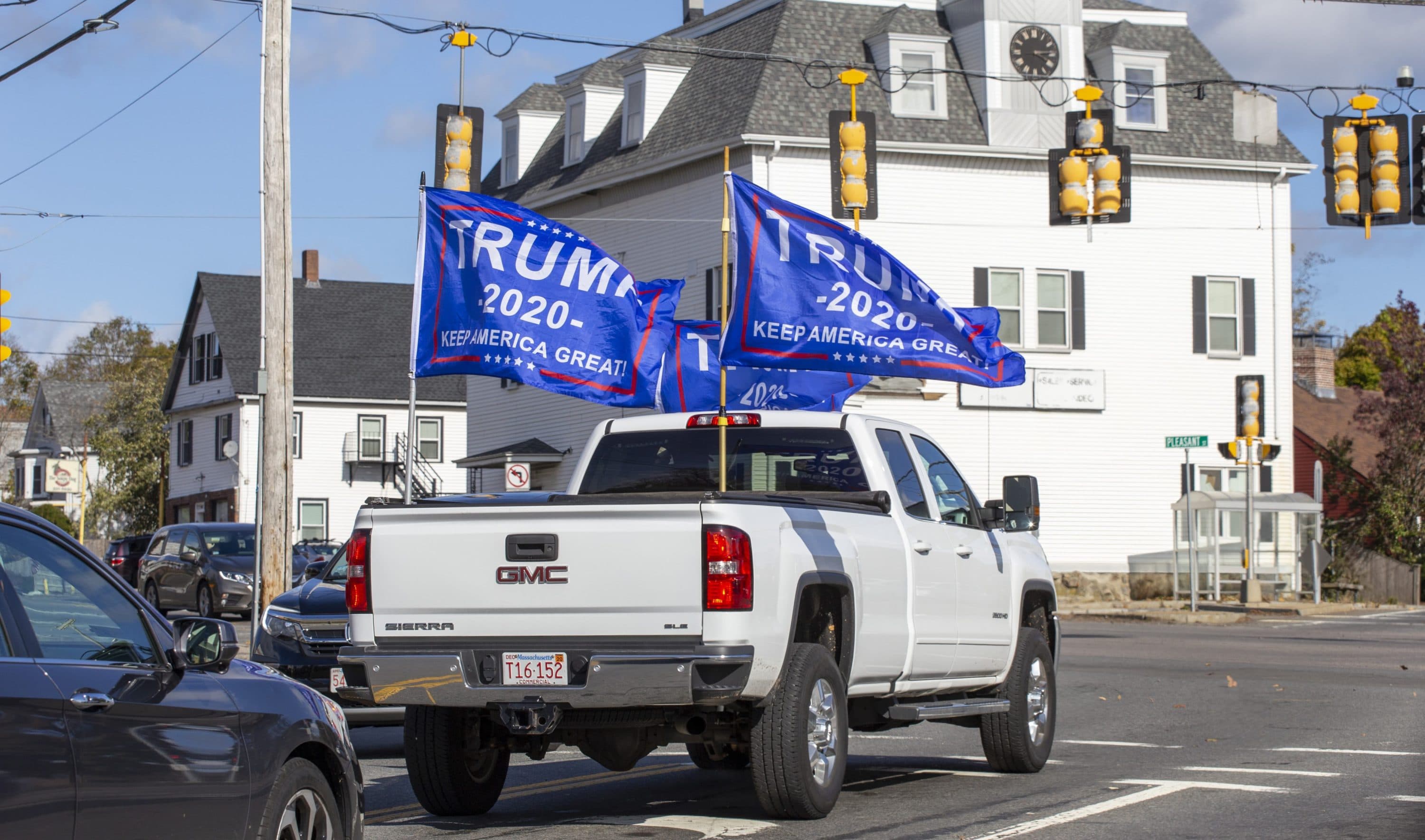 A supporter of President Donald Trump drives around Weymouth on election day flying Trump flags. (Joe Difazio for WBUR)