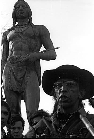 Wamsutta Frank James by statue of Massasoit, in Plymouth, MA on the National Day of Mourning in the 1970s. (Courtesy of guest)