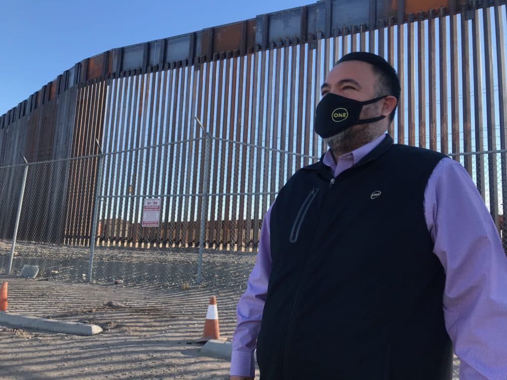 Matias Rosales, vice mayor of San Luis, Arizona, stands in the shadow of a new section of President Trump's border wall. (Peter O'Dowd/Here &amp; Now)