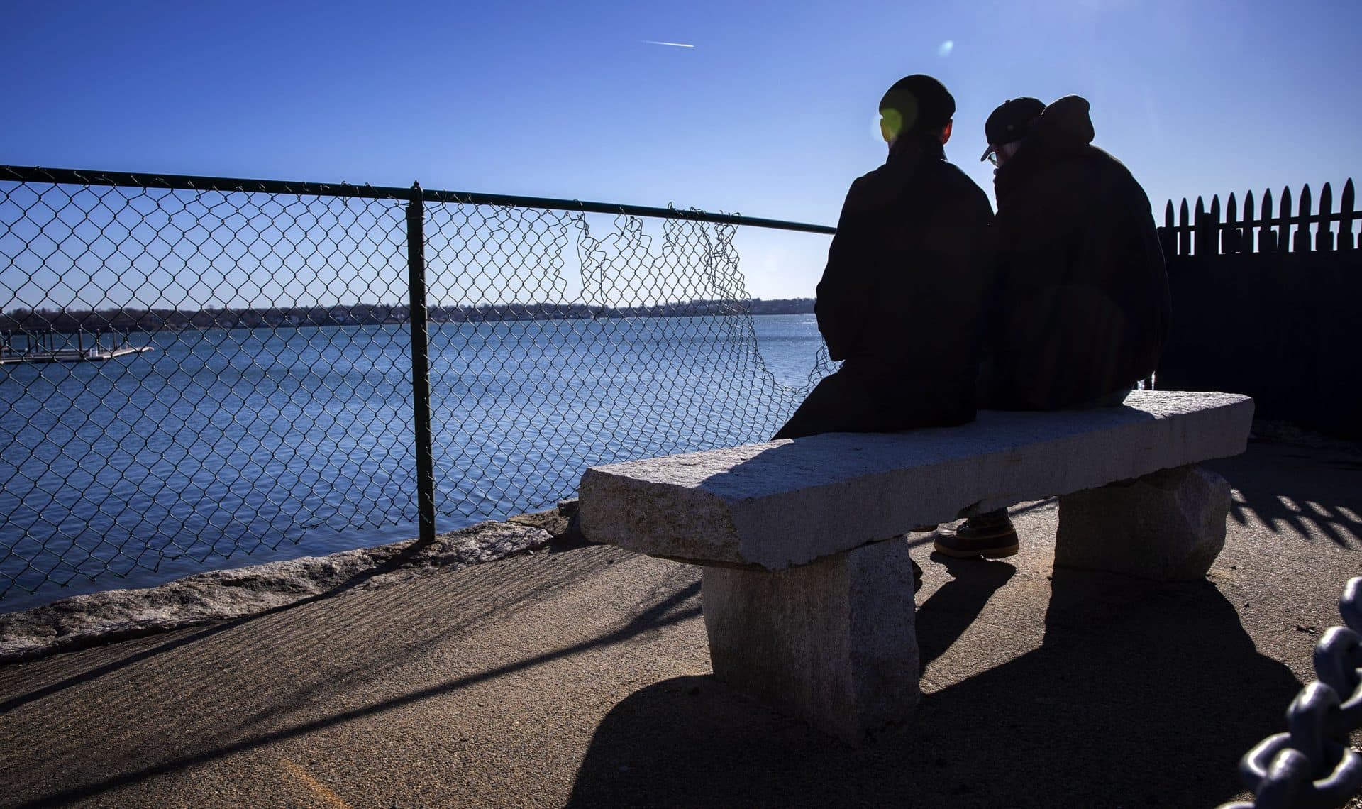 Jeremiah MacKinnon and Frank Shaw on a stone bench overlooking Salem Harbor. (Robin Lubbock/WBUR)