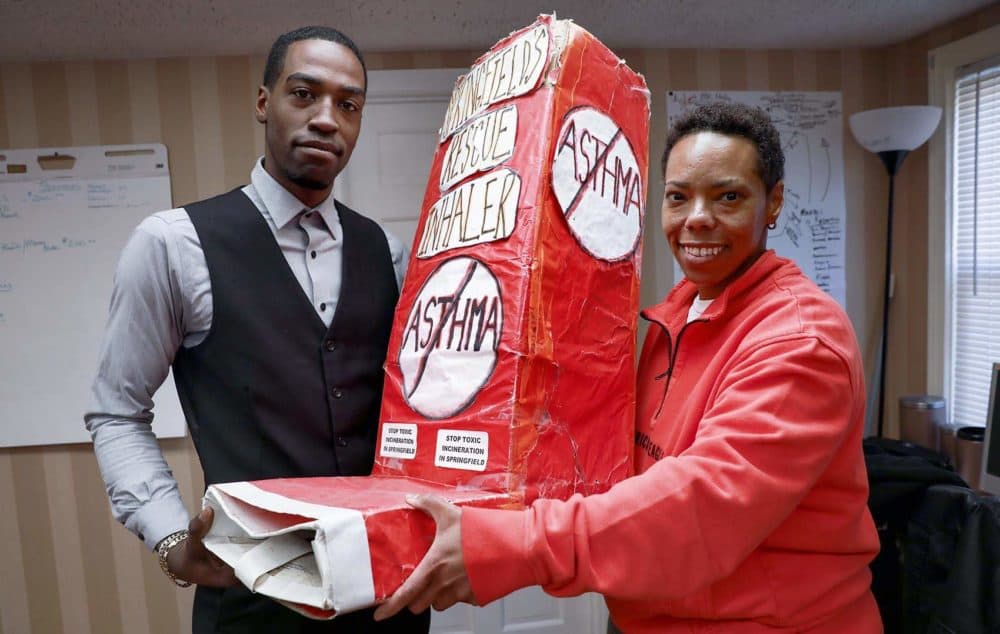 Syair Bey and Tanisha Arena display the model inhaler activists use in protests against the Palmer biomass plant. (Robin Lubbock/WBUR)