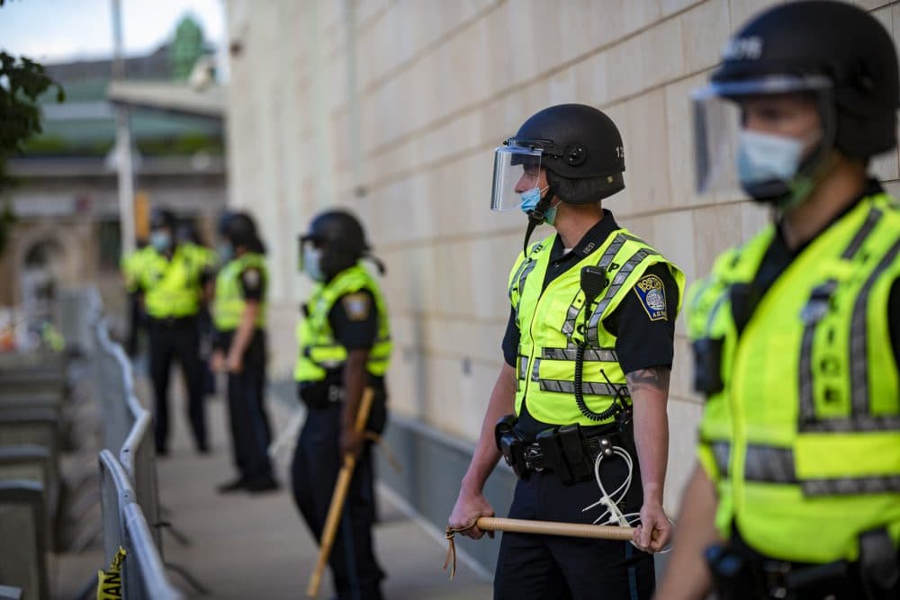 Boston police officers with batons lined up outside the District B-2 station in Roxbury before a protest on May 31, 2020. (Jesse Costa/WBUR)