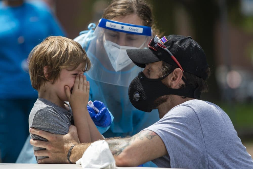 A young boy cries to his father after being tested for COVID-19 at the free testing being offered by the state in Chelsea Square. (Jesse Costa/WBUR)