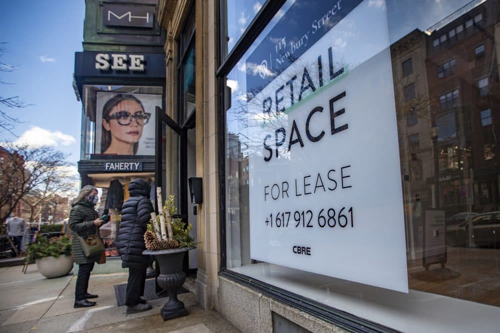 Two shoppers walk into a store next to a vacant retail spot for lease on Newbury Street. (Jesse Costa/WBUR)