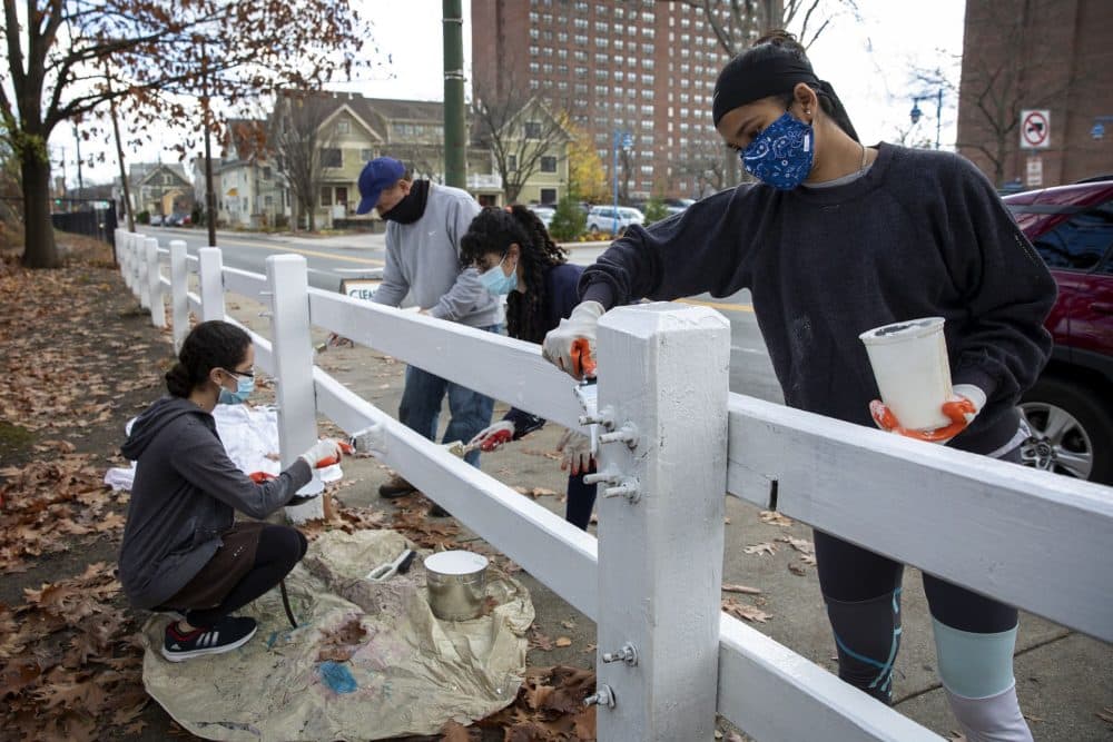 Oaisharja Barua paints the fence on Rindge Avenue by Jerry's Pond. (Robin Lubbock/WBUR)