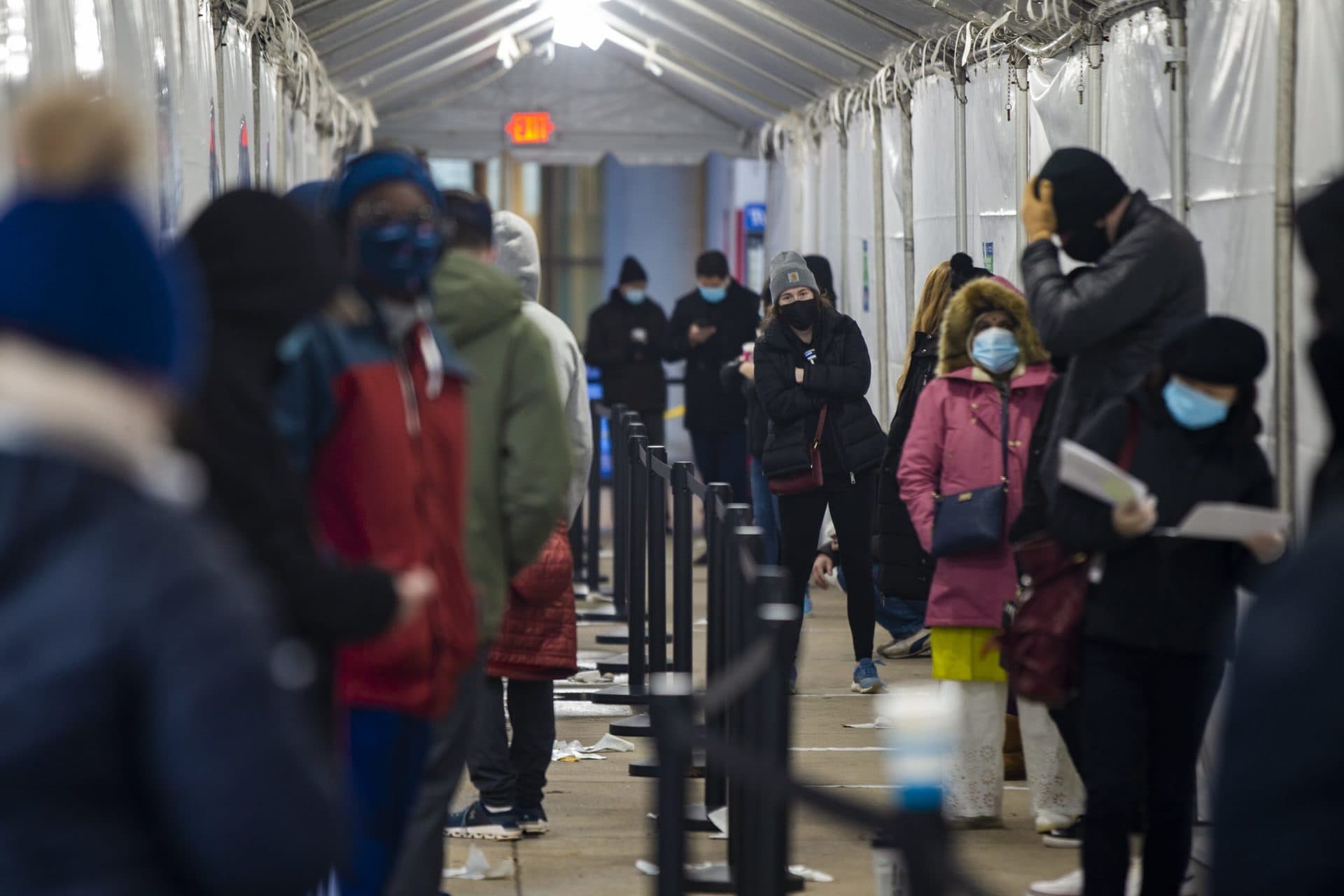 A woman looks towards the front of the line of people waiting for testing outside of the Tufts Medical COVID-19 Testing Center on Tremont Street. (Jesse Costa/WBUR)