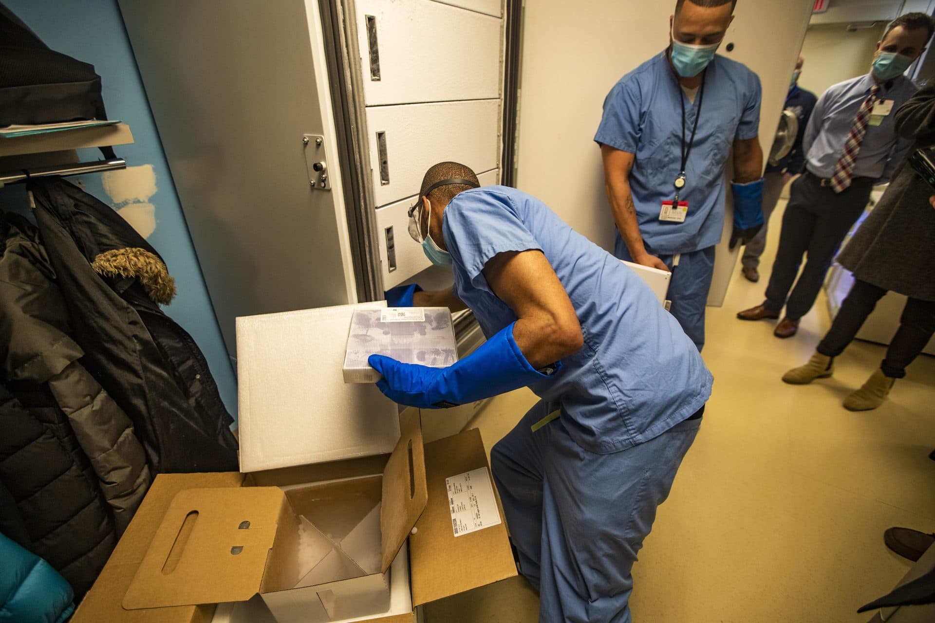 Boston Medical Center pharmacy technical worker William Senior places two trays of the coronavirus vaccine into a freezer, kept at temperatures between -60 and -80 degrees, which was just delivered at 5:45 a.m. to the hospital. (Jesse Costa/WBUR)