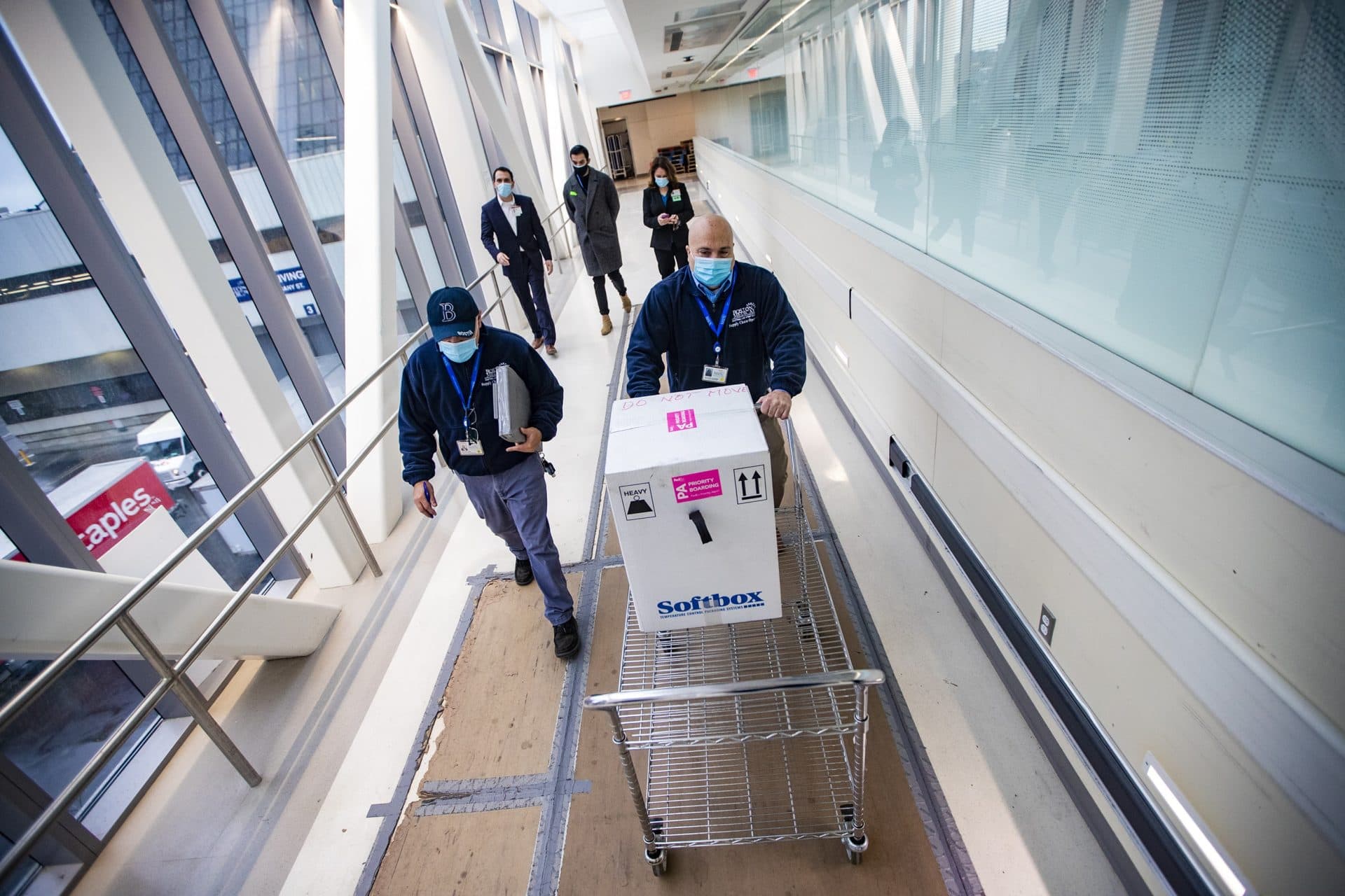 Richard Guarino, Boston Medical Center supply chain operations associate director, wheels a cart containing Pfizer's COVID-19 vaccine to the pharmacy. (Jesse Costa/WBUR)