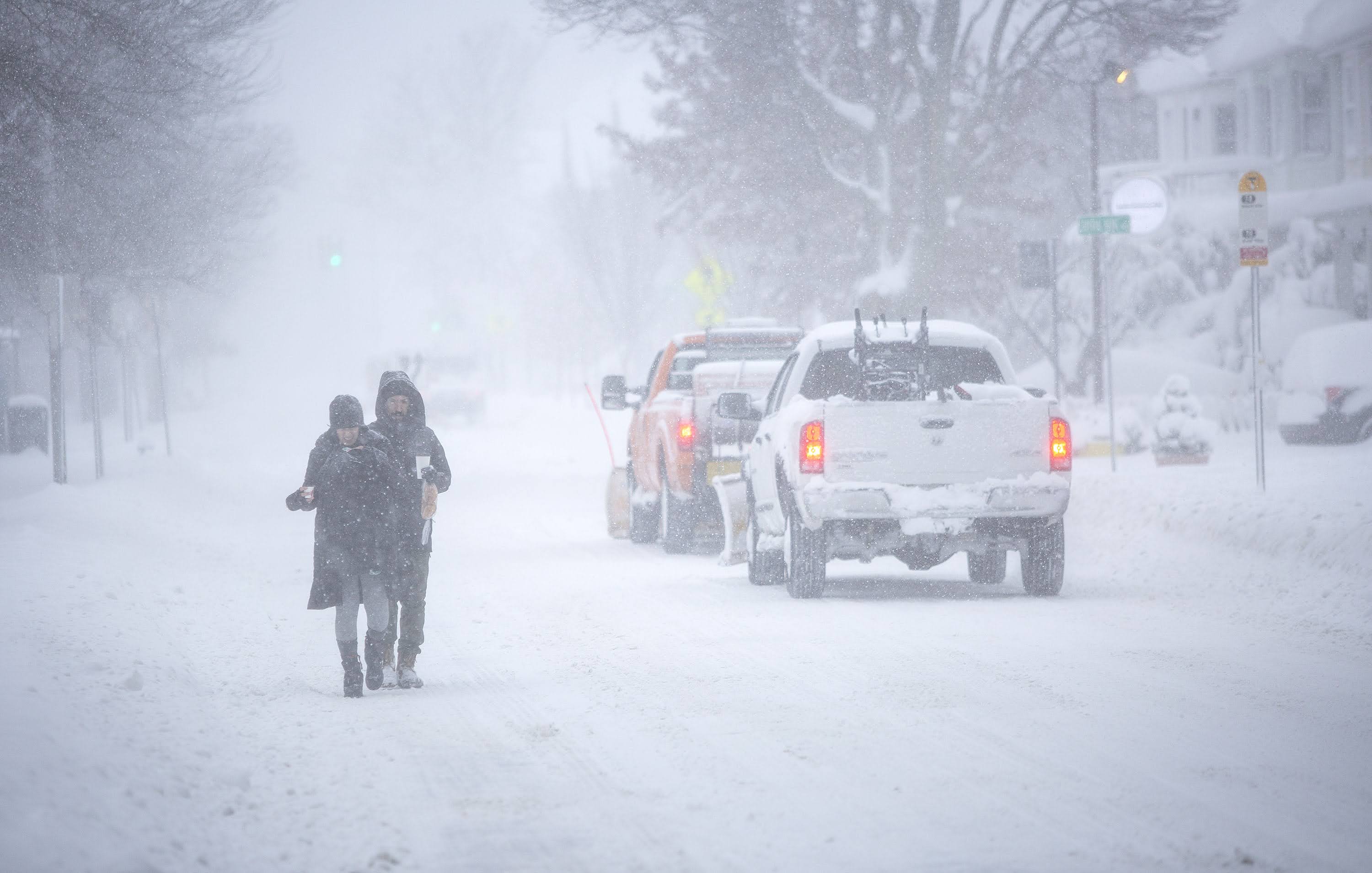 With the sidewalk deep in snow, pedestrians walk along the side of the road on Concord Ave. (Robin Lubbock/WBUR)