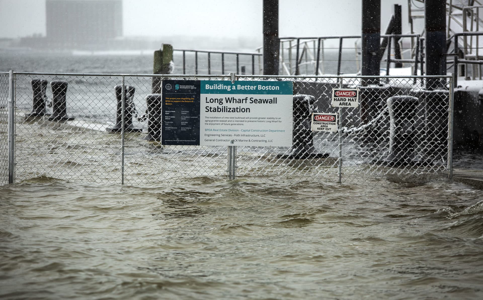 The fence around a "Building A Better Boston" project gets its feet wet as high tide during the snow storm floods across Long Wharf. (Robin Lubbock/WBUR)