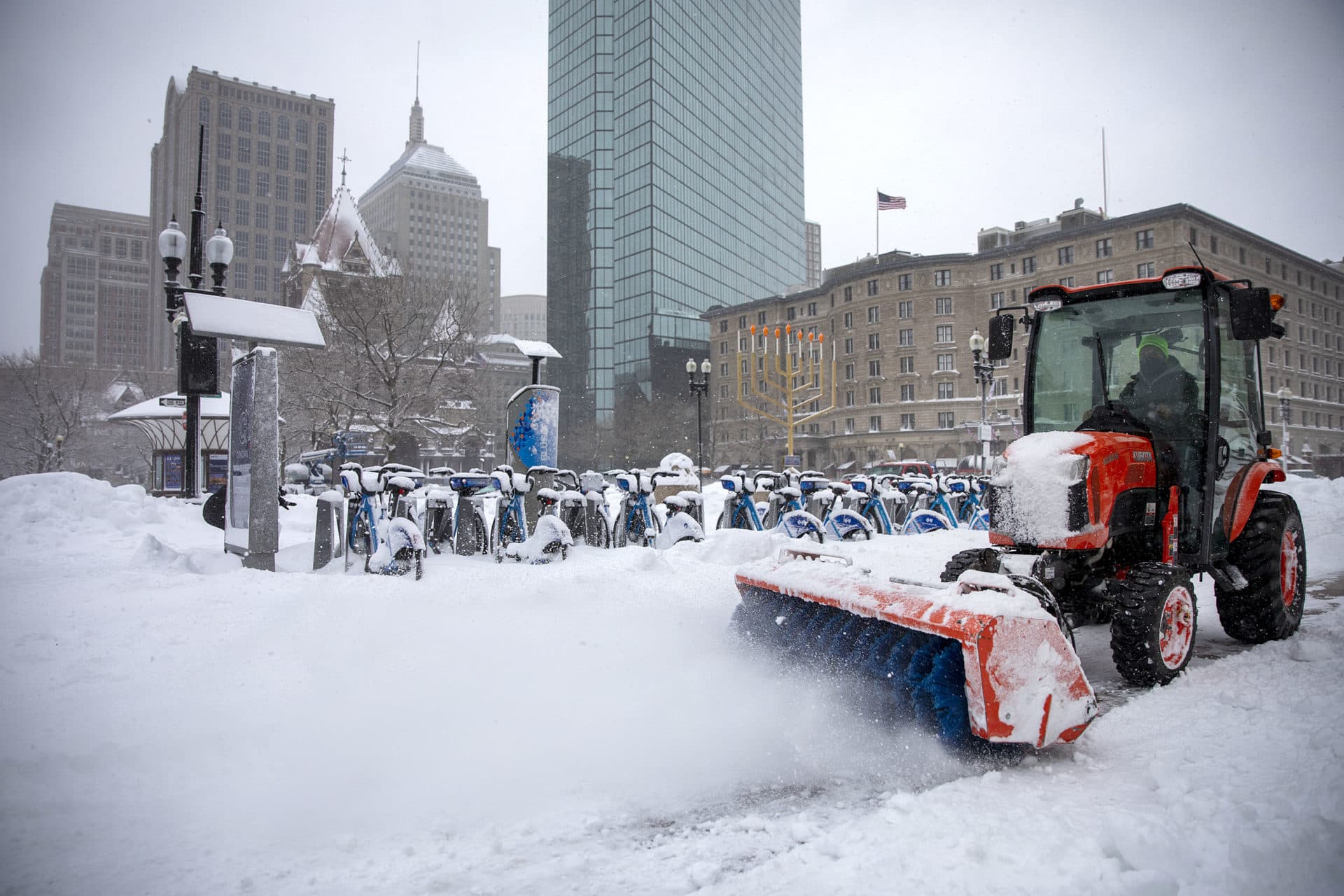A tractor with a large brush sweeps snow from the sidewalk in Copley Square. (Robin Lubbock/WBUR)
