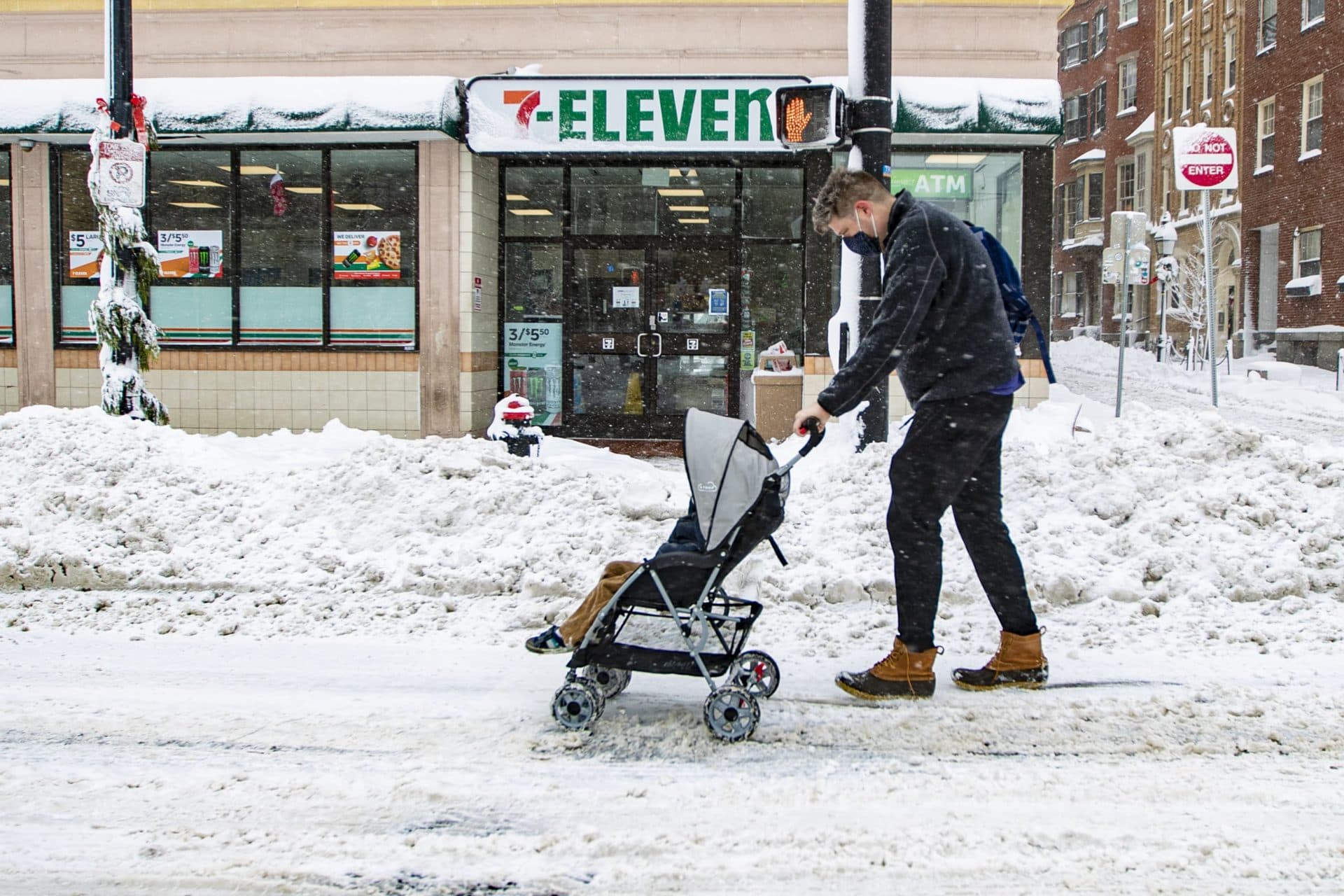 A man pushes a baby in a stroller down Cambridge Street. (Jesse Costa/WBUR)
